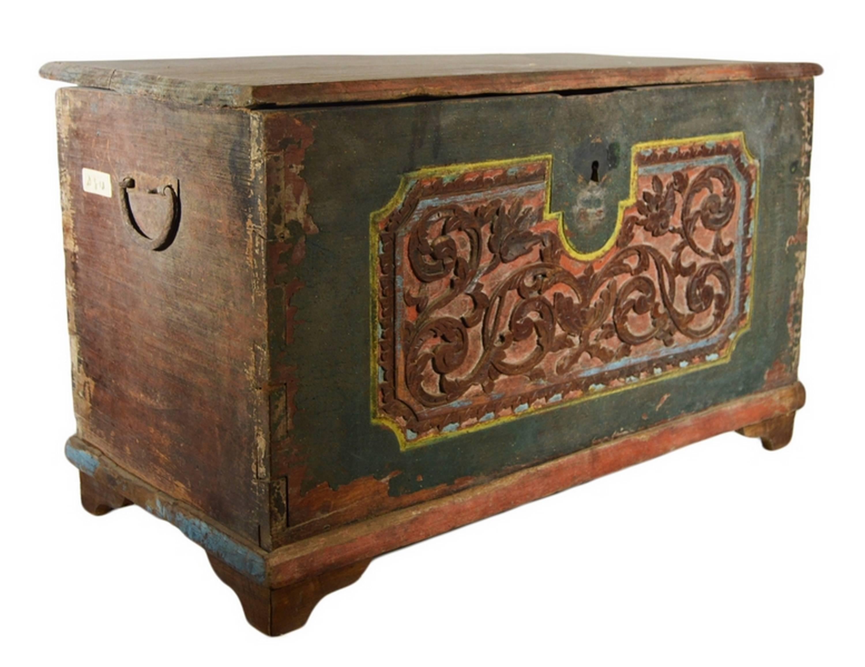 A 19th century hand-carved and painted Indonesian trunk with foliage motifs. This rectangular trunk rests on four small round legs. The front is entirely painted and hand-carved. The centre displays a colorful hand-carved frame with foliage on a red