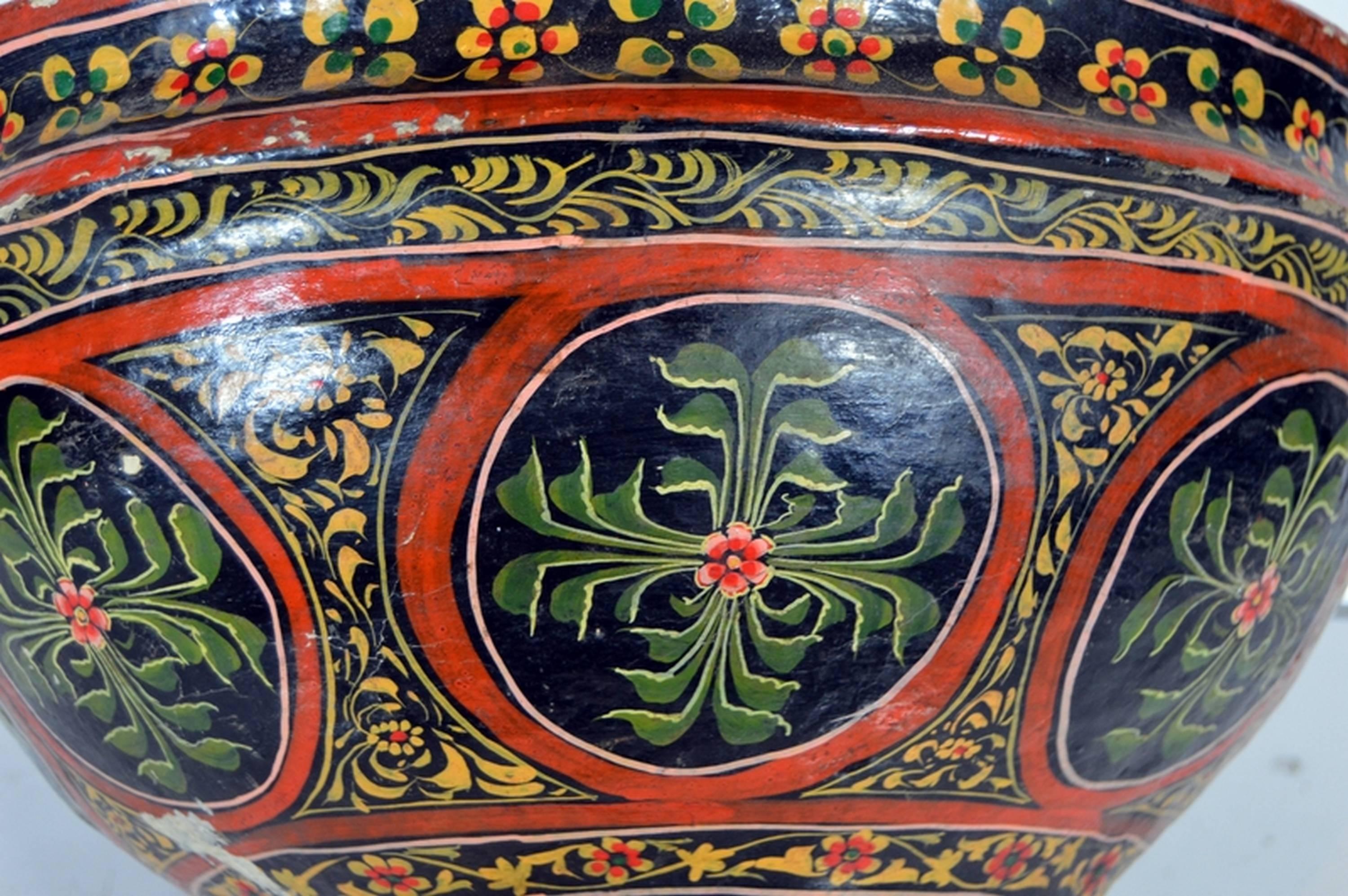 A large 19th century papier-mâché. bowl hand-painted with black and red flower patterns from India. The bowl features a black background with a flower frieze on the top and bottom. The belly showcases a frieze of large medallions with flowers and