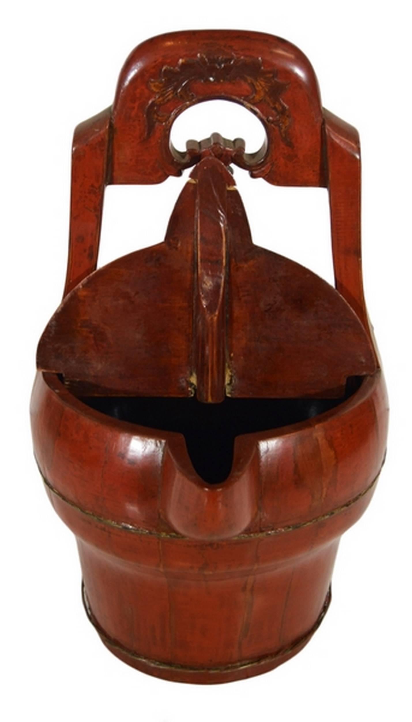 A 19th century Chinese basket with spout, hand-carved and lacquered in red. This circular basket displays a globular belly mounted on a cylindrical base. The flat top opens thanks to a hinged half-lid and a spout. This basket showcases a tall handle
