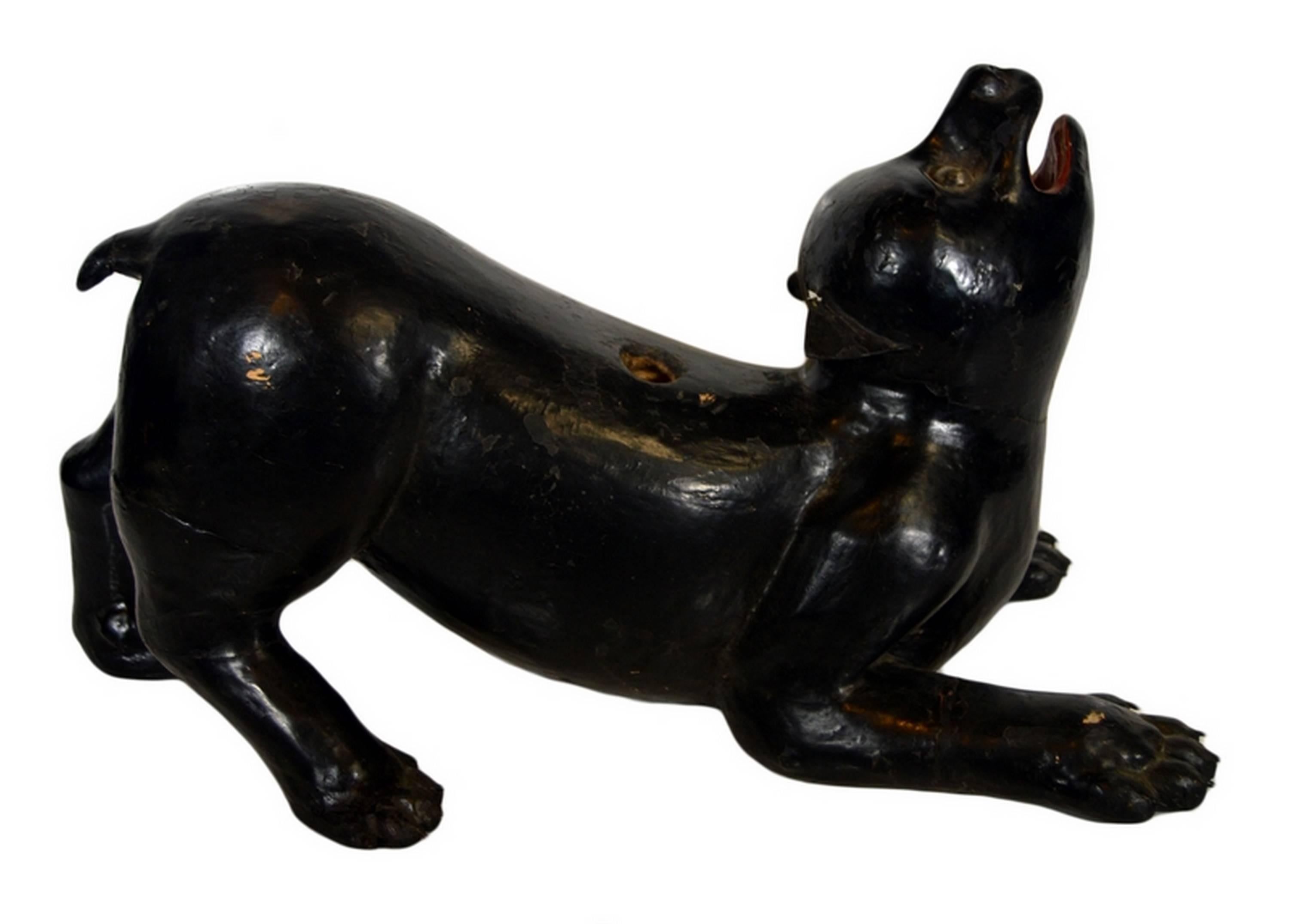 A 19th century Burmese dog temple statue hand carved in wood in Burma. This painted black dog is depicted with a lively attitude, half stretched out and barking. Its face is enlivened by the red paint added to its mouth and by the glass details of