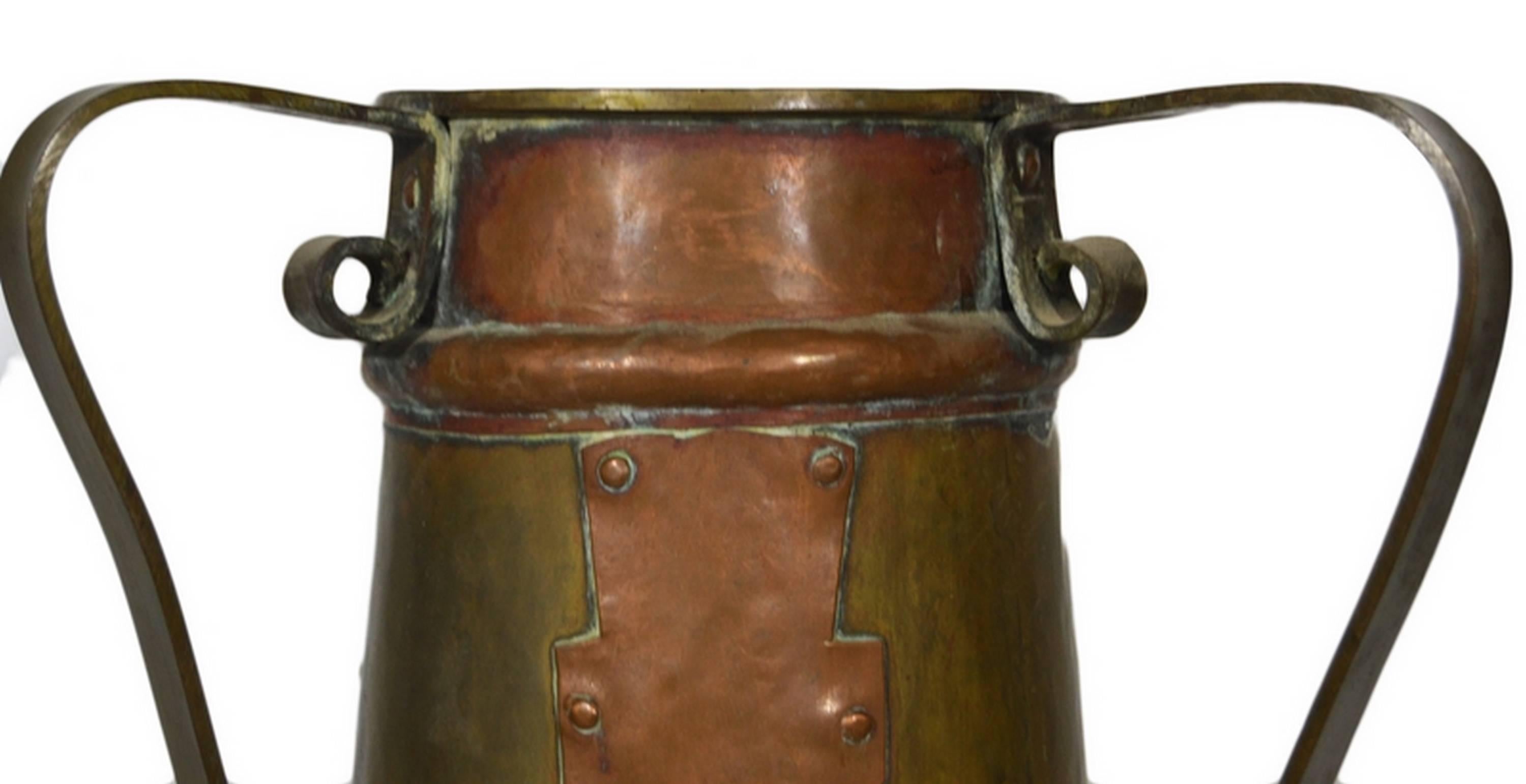 A vintage bi-color pitcher hand-hammered in copper in early 20th century, India. This pitcher adopts a cylindrical shape with three vertical sections and three scroll handles. The top and bottom sections display hammer marks and a rounded rod. The