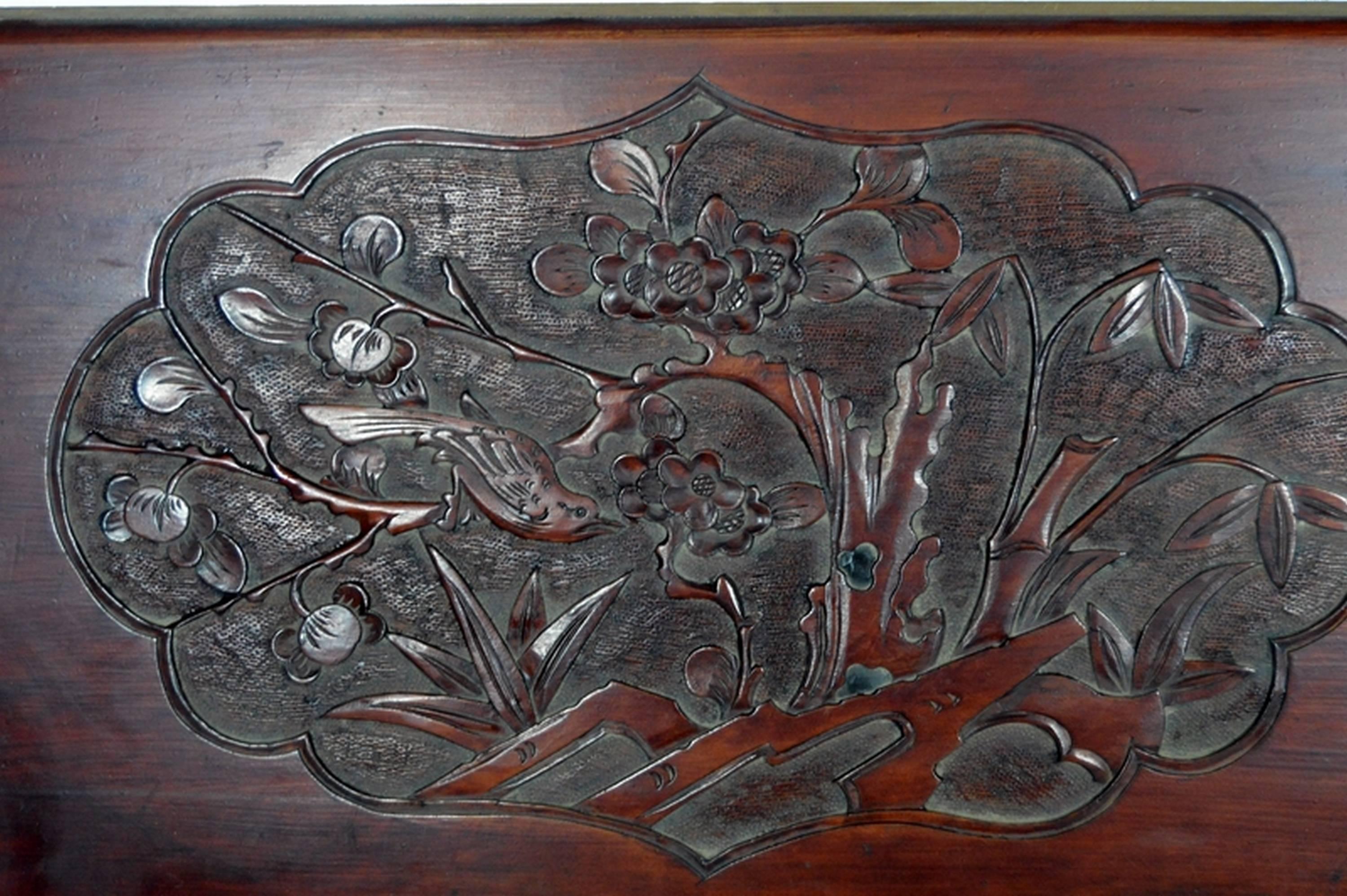 A 19th century Chinese wall plaque hand-carved in lacquered rosewood. This large rectangular wall plaque displays a lobed medallion on its centre. The hand carved frame showcases an enjoyable flower and bird scene, a common and auspicious pattern in
