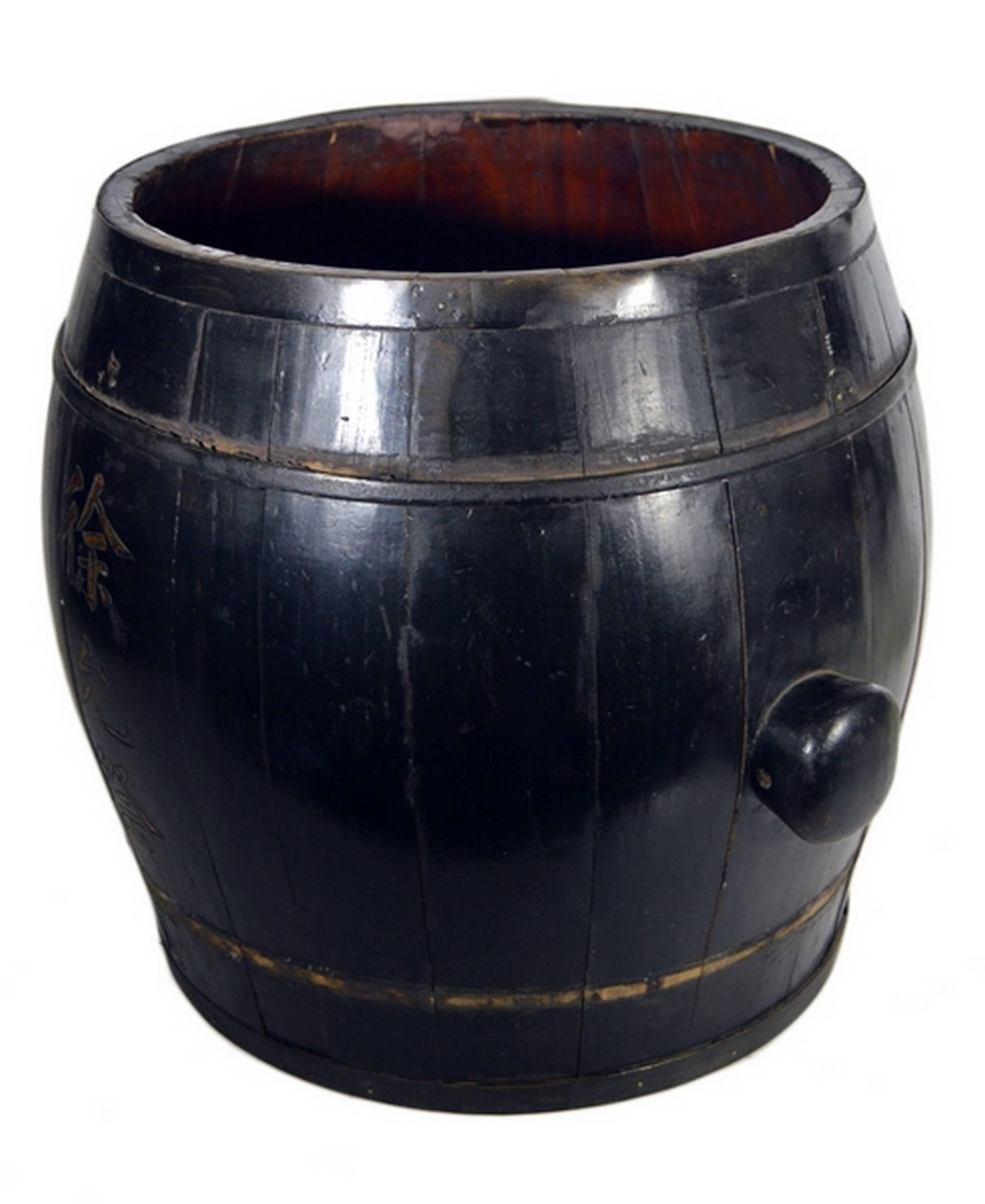A 19th century Chinese grain barrel / basket with calligraphy on the sides. This round barrel is made with black lacquered wood planks and features two round knobs on the sides for lifting. The basket is adorned with two  calligraphy columns,
