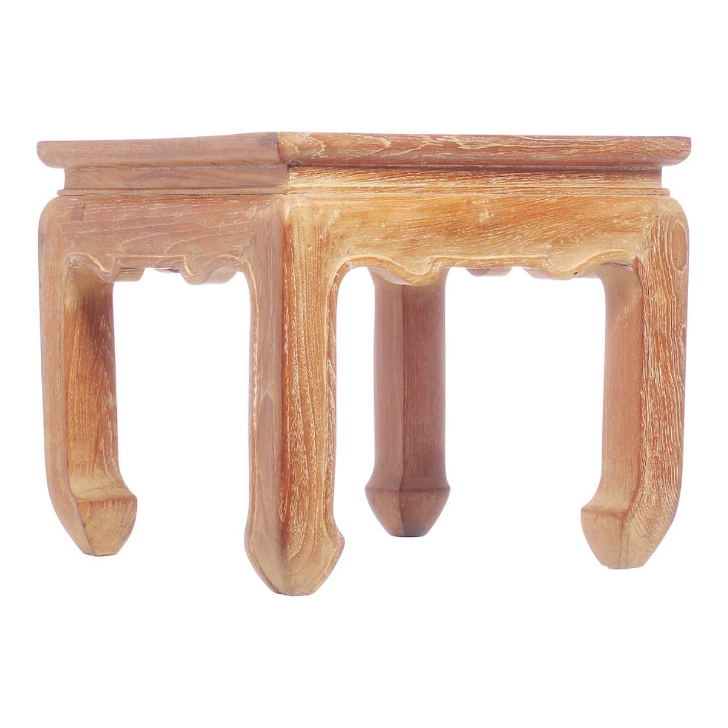 This 20th century Thai small side table was made with bleached teakwood. The table adopts a cubic shape with a recess and a brace panel under its square top. The four legs are curved on their extremities and adorned with a carved lip on their inner