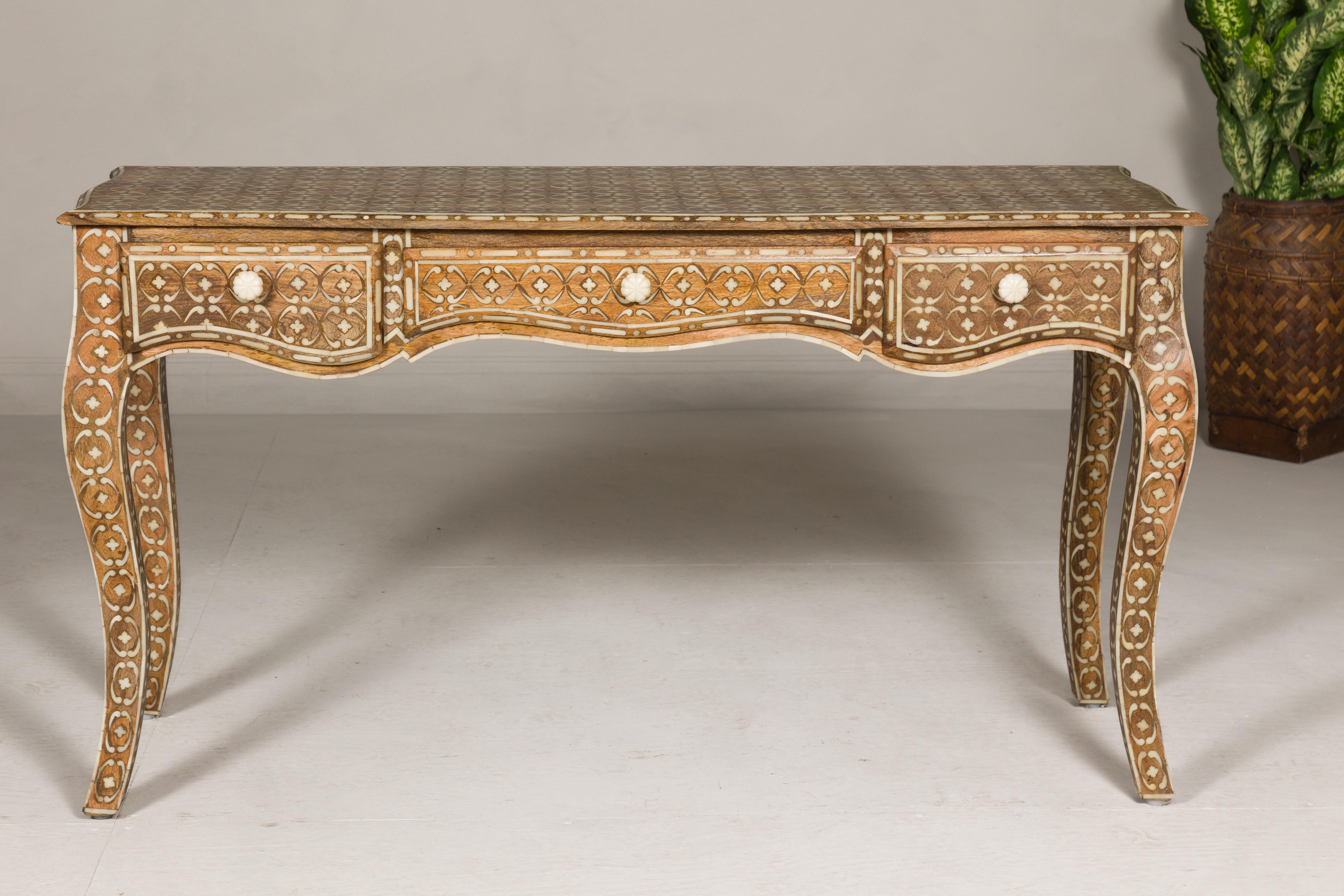 Anglo-Indian Louis XV style mango wood console table or desk with inlaid bone décor. Exuding the grandeur of Anglo-Indian style craftsmanship, this Louis XV inspired console table is a masterpiece carved from robust mango wood. Its exquisite inlay