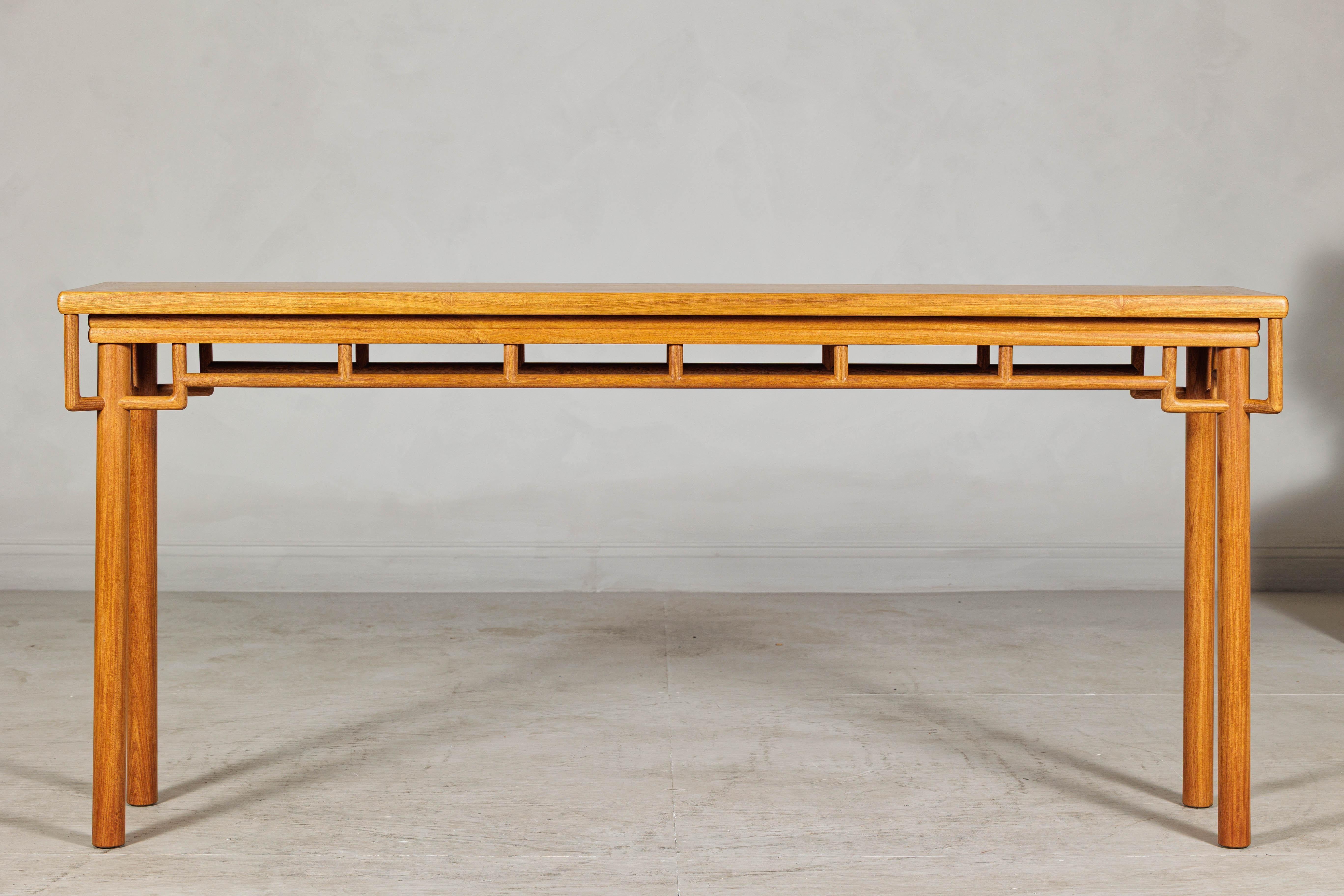 This Chinese console table is distinguished by its graceful proportions and refined linear construction. Made of warmly toned elmwood with a smooth finish, the design is anchored by a striking humpback-style stretcher that runs the full perimeter