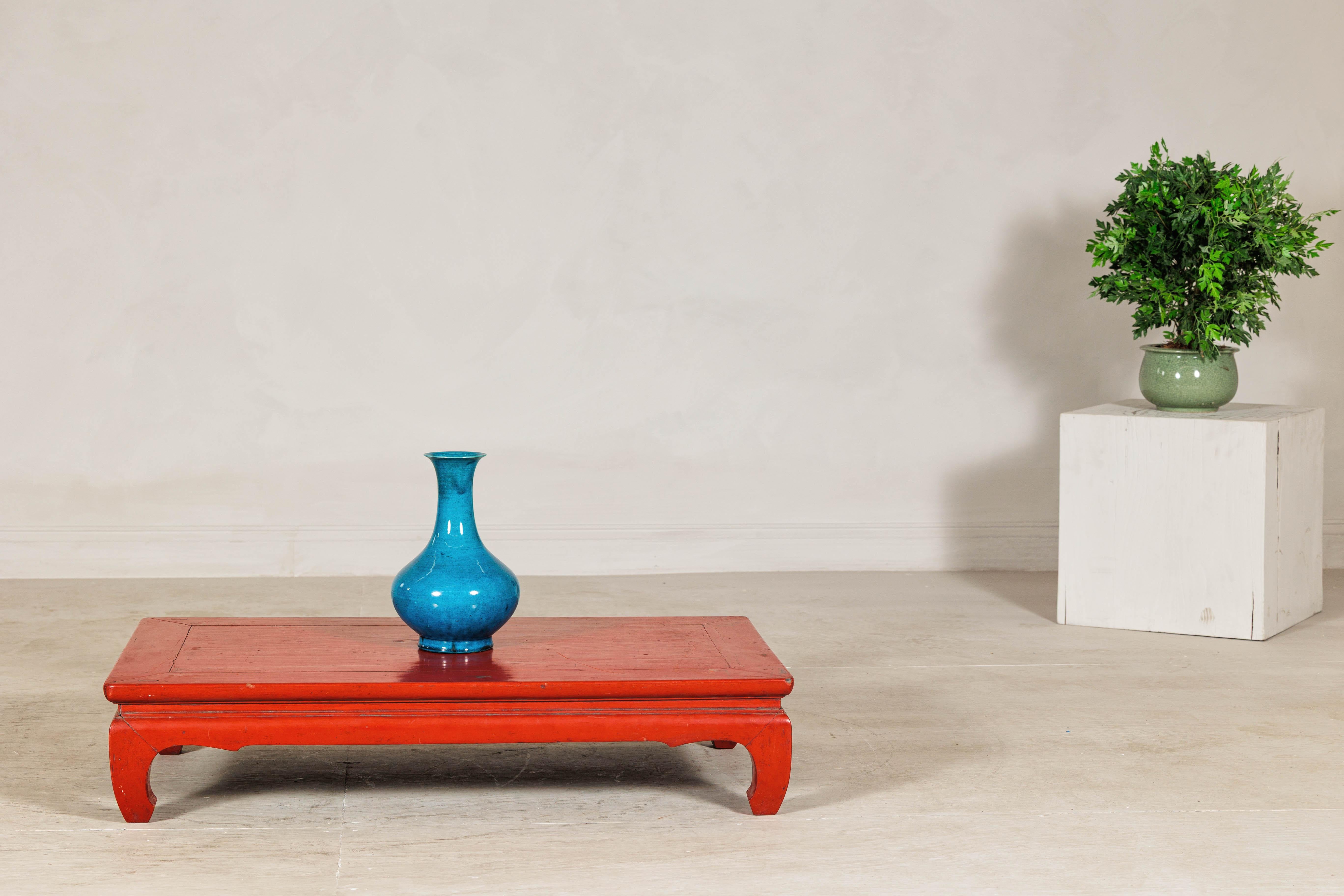 Cette table basse chinoise vintage présente une finition laquée rouge vif et une silhouette raffinée ancrée par des pieds traditionnels en forme de chow. Le plateau rectangulaire affleure le cadre, soulignant les proportions horizontales de la table
