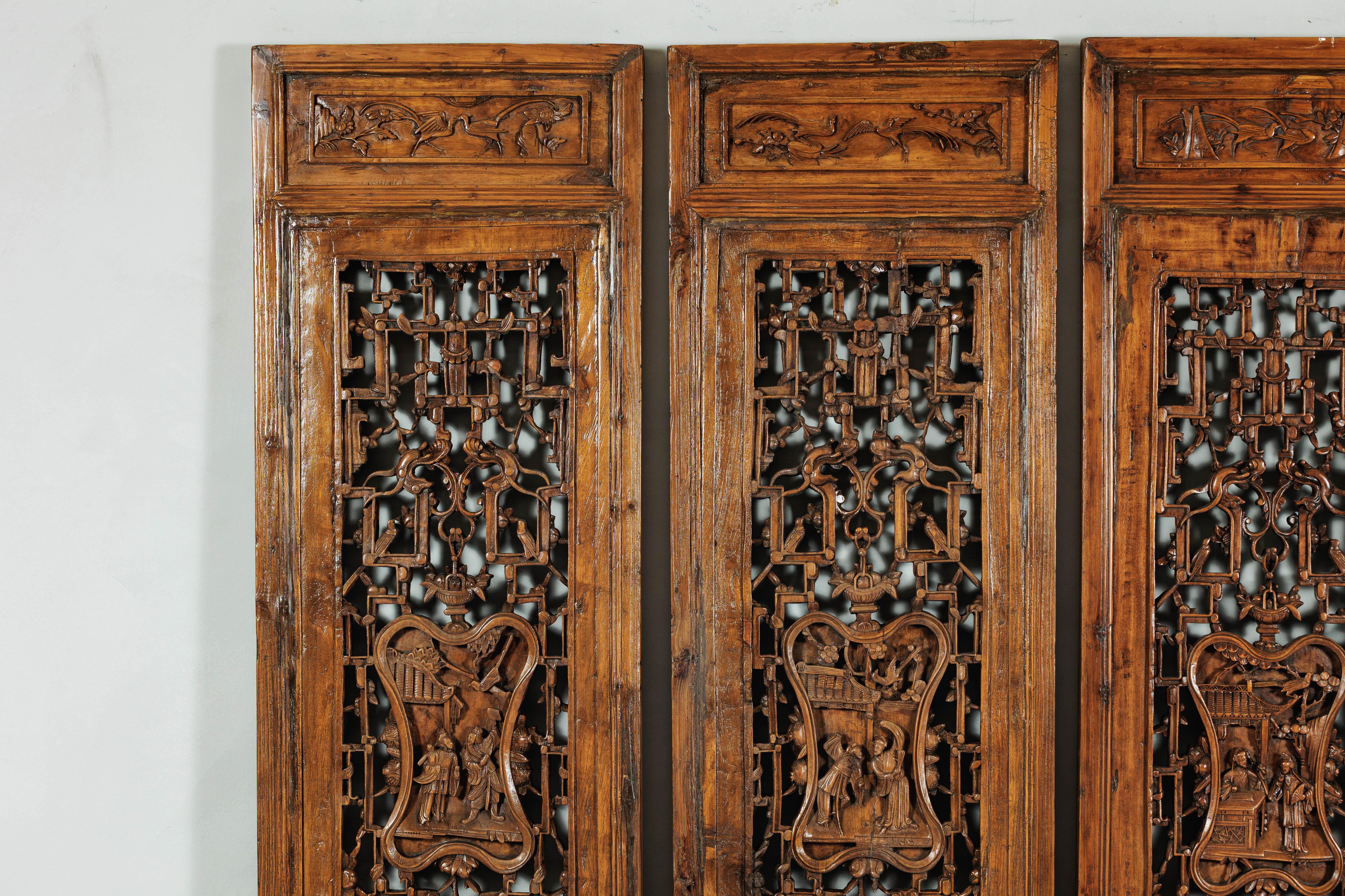 Cet ancien paravent chinois à quatre panneaux est composé de panneaux de bois sculptés individuellement, chacun présentant un motif de treillis géométrique finement percé et un cartouche central avec des scènes figuratives profondément sculptées.