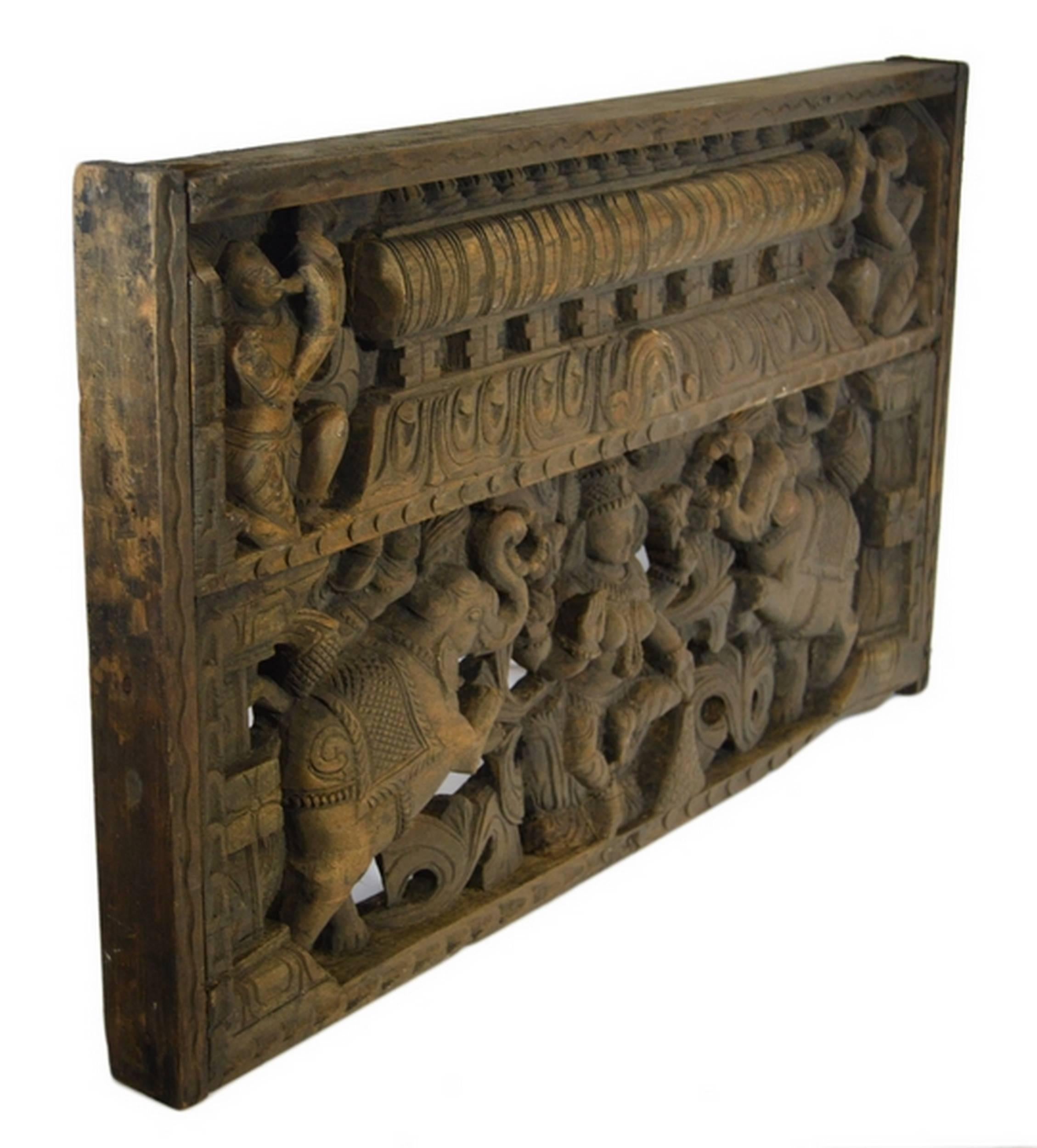 An early 20th century religious temple plaque hand-carved of Sheesham wood in India. This small rectangular plaque displays two sections with several characters. The bottom section showcases a Hindu goddess, perhaps Shiva (third eye on its forehead,
