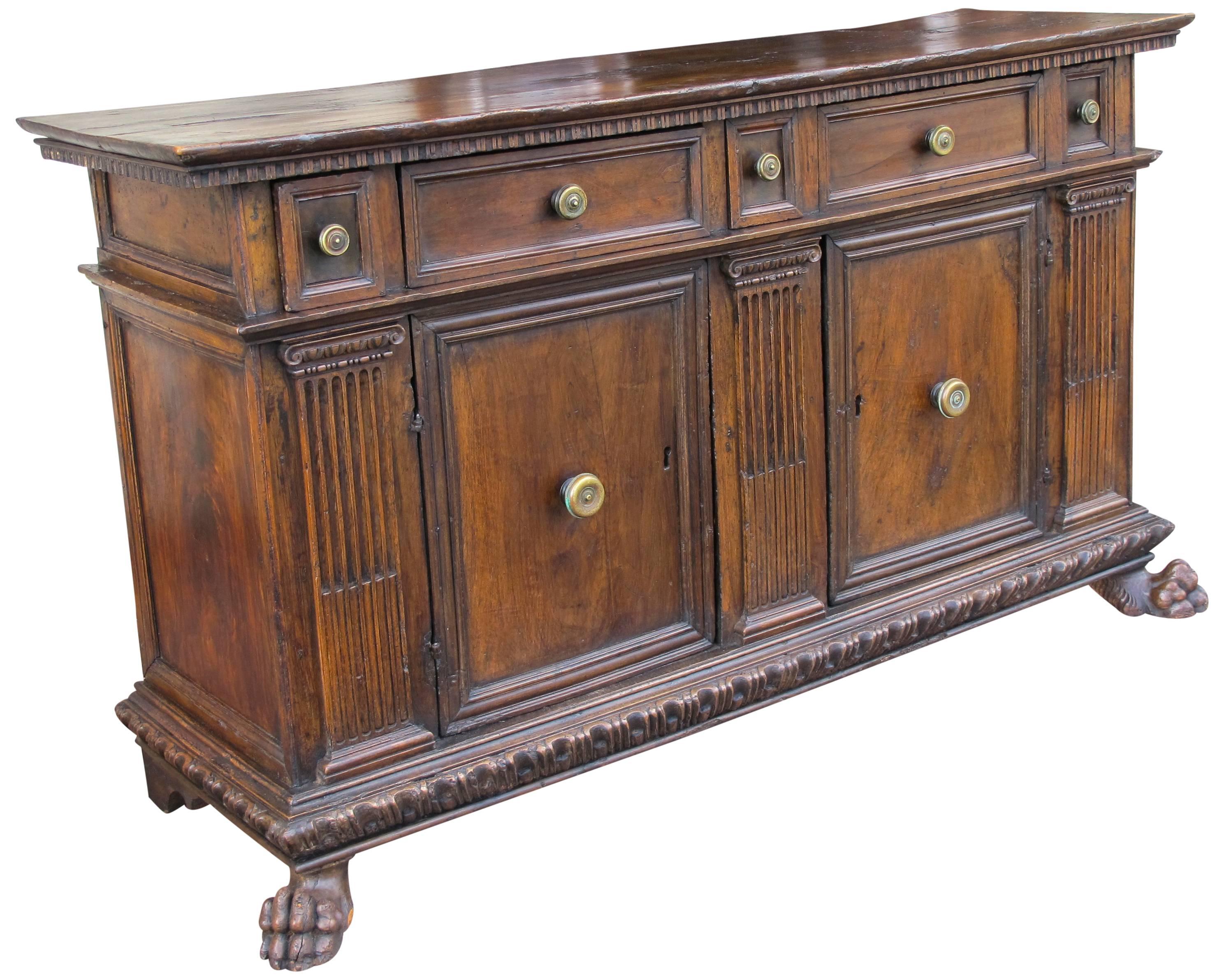 Extremely fine and rare 16th Century Italian Credenza composed of walnut with bronze pulls. 
Rectangular top with dentil molding on top of 5 top drawers separated by a molding with two large doors with bronze pulls. Flanked by three carved columns.