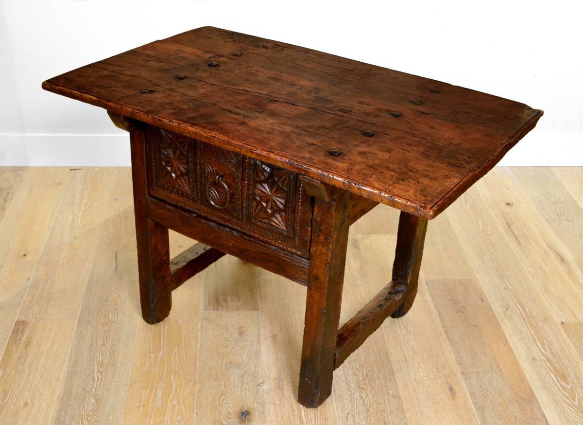 A good Spanish Baroque period chestnut side table with a hand adzed rectangular top over a heavily carved drawer, raised on square legs and joined by end stretchers, circa 1750.
Accessories shown for scale only.
Dimensions: 42.5 inches wide x 26