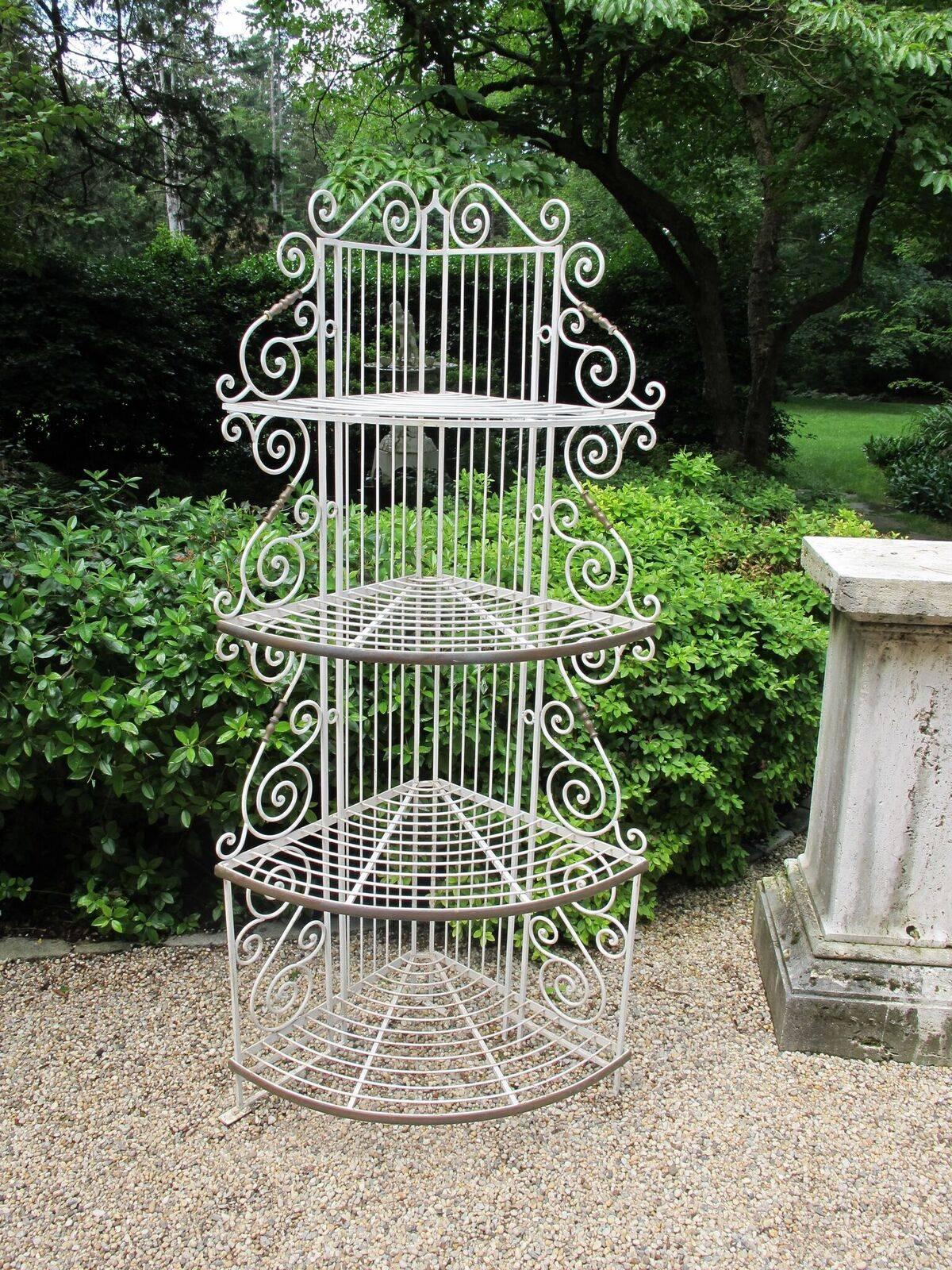 A wrought iron corner baker’s rack, painted white, with scrollwork and brass decorative elements, French, circa 1950. Measures: 85.5 ins. high, 36.5 ins. wide, 25 ins. deep.