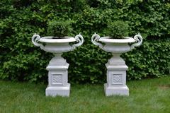 A Pair of White Painted Cast-Iron Urns on Pedestals