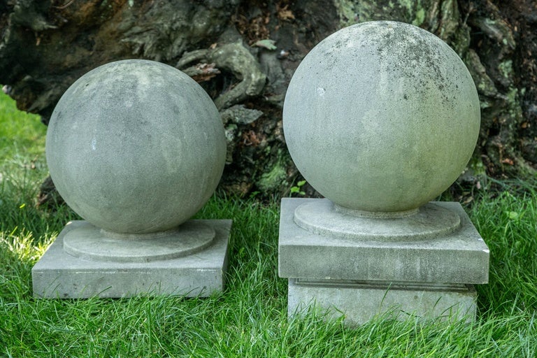 A pair of carved limestone ball finials raised on short socles and integral square bases.