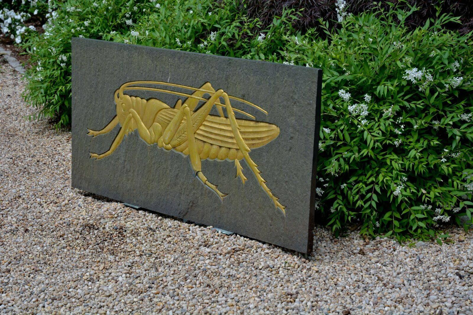 A carved and gilded Westmoreland slate relief plaque of a grasshopper with stand, English, circa 1930. Measures: 26 ins. high, 53 ins. wide.