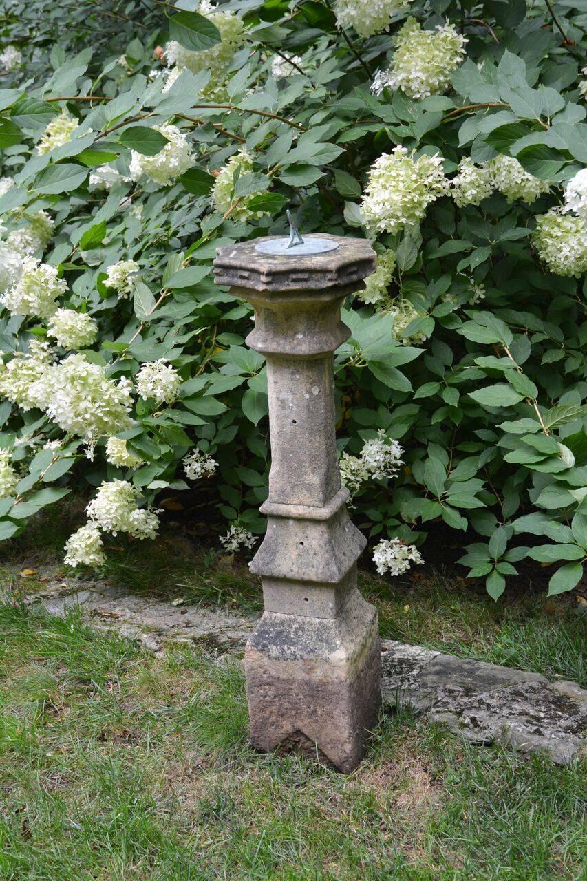 A carved stone baluster, the top with reverse scalloped edge, surmounted by bronze sundial plate, English, circa 1870. Measure: 40 ins. high overall, extension on bottom meant to be buried to achieve 32 ins. high, top diameter 12 ins. Reputed to