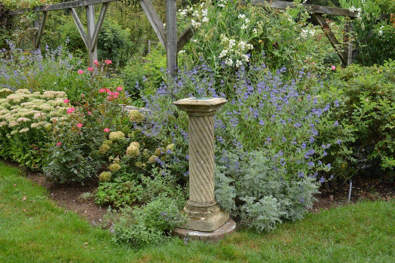 A carved Cotswold stone wrythen baluster with stepped square base and square top, with replaced later bronze sundial plate, English, circa 1900. Measure: 44.25 ins. high including gnomon. 41 ins. high to top of pedestal; 13 ins. square at top., 13.5