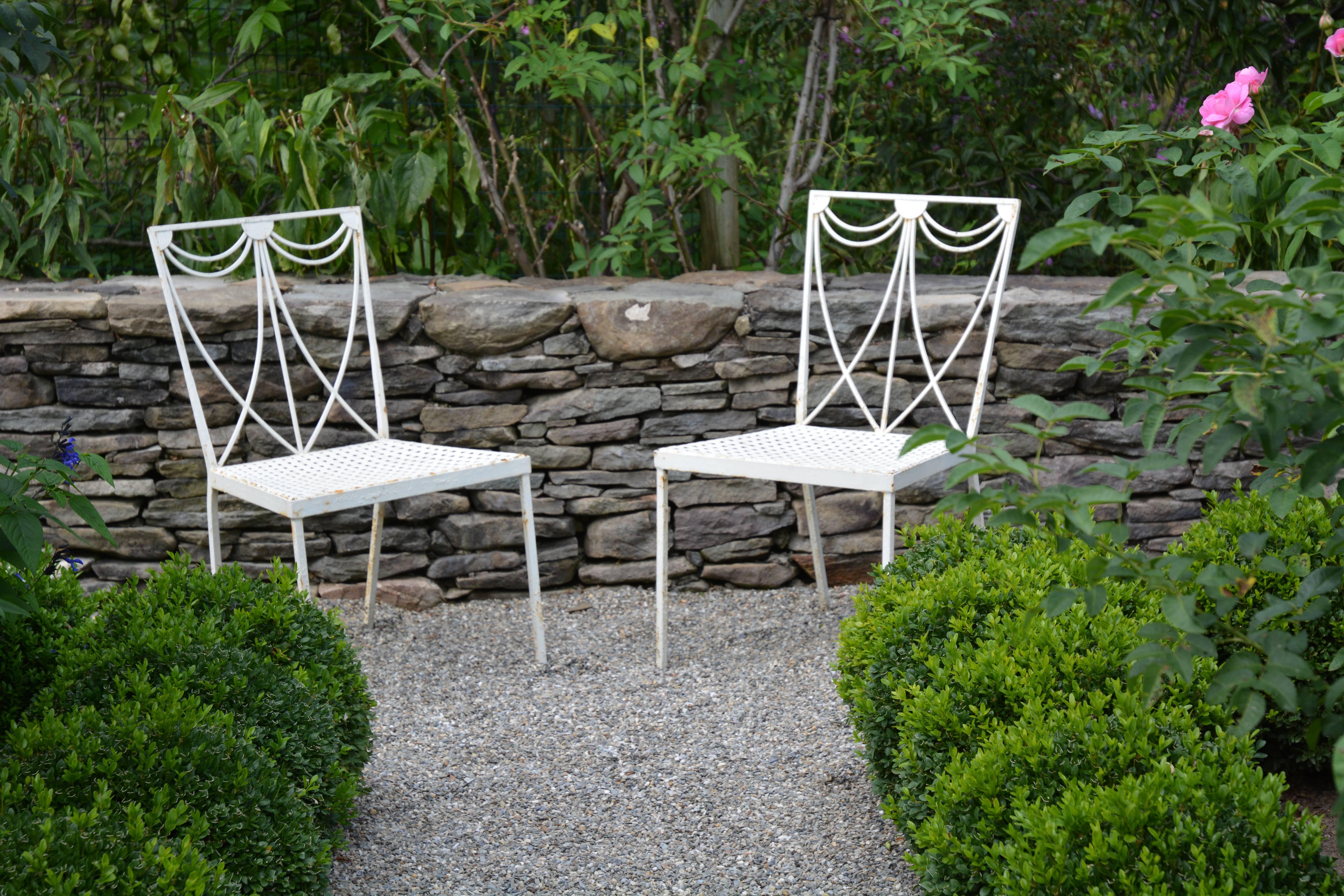 A pair of wrought iron chairs with simple, modern neoclassical swag motif on the back with basket weave seat, possibly by the Joseph J. Leinfelder firm of Lacrosse, WI.
