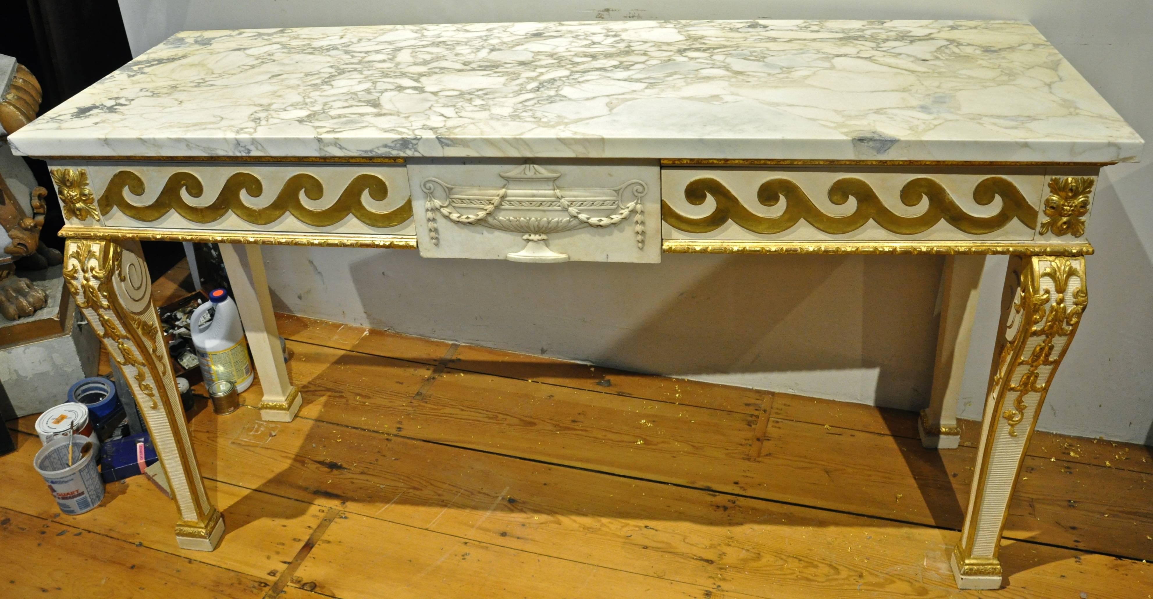 Late 19th century Irish parcel-gilt console table in style of William Kent

marble top.
Carved giltwood and painted elements.
Running dog detail to reveal two drawers flanking a central carved marble plaque of a neoclassical urn,
early 18th