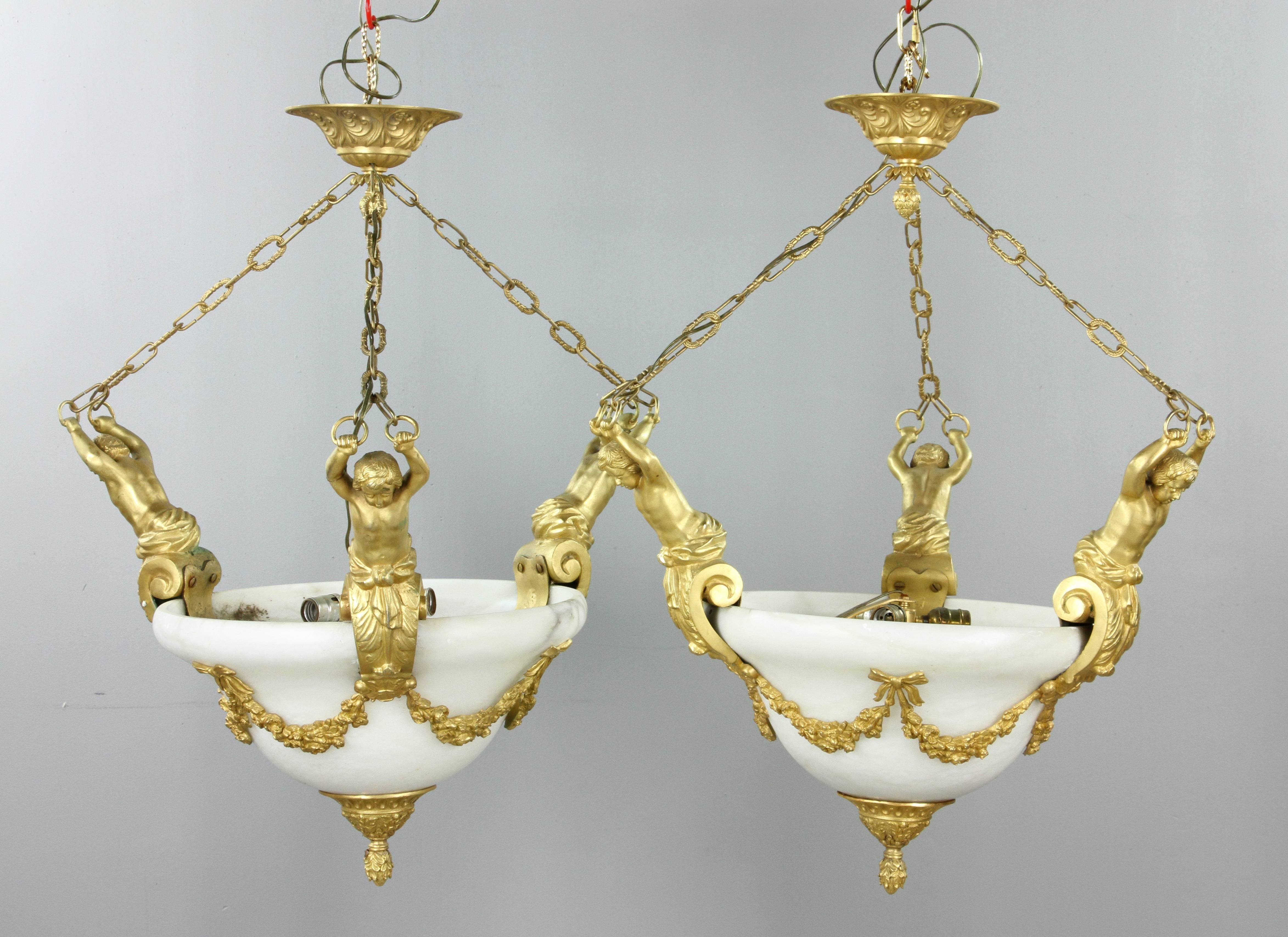 Pair of Louis XVI style gilt bronze ormolu and marble chandeliers.

Having neoclassical gilt bronze figural arms garland motif and white marble bowls.
From a Palm Beach Estate.