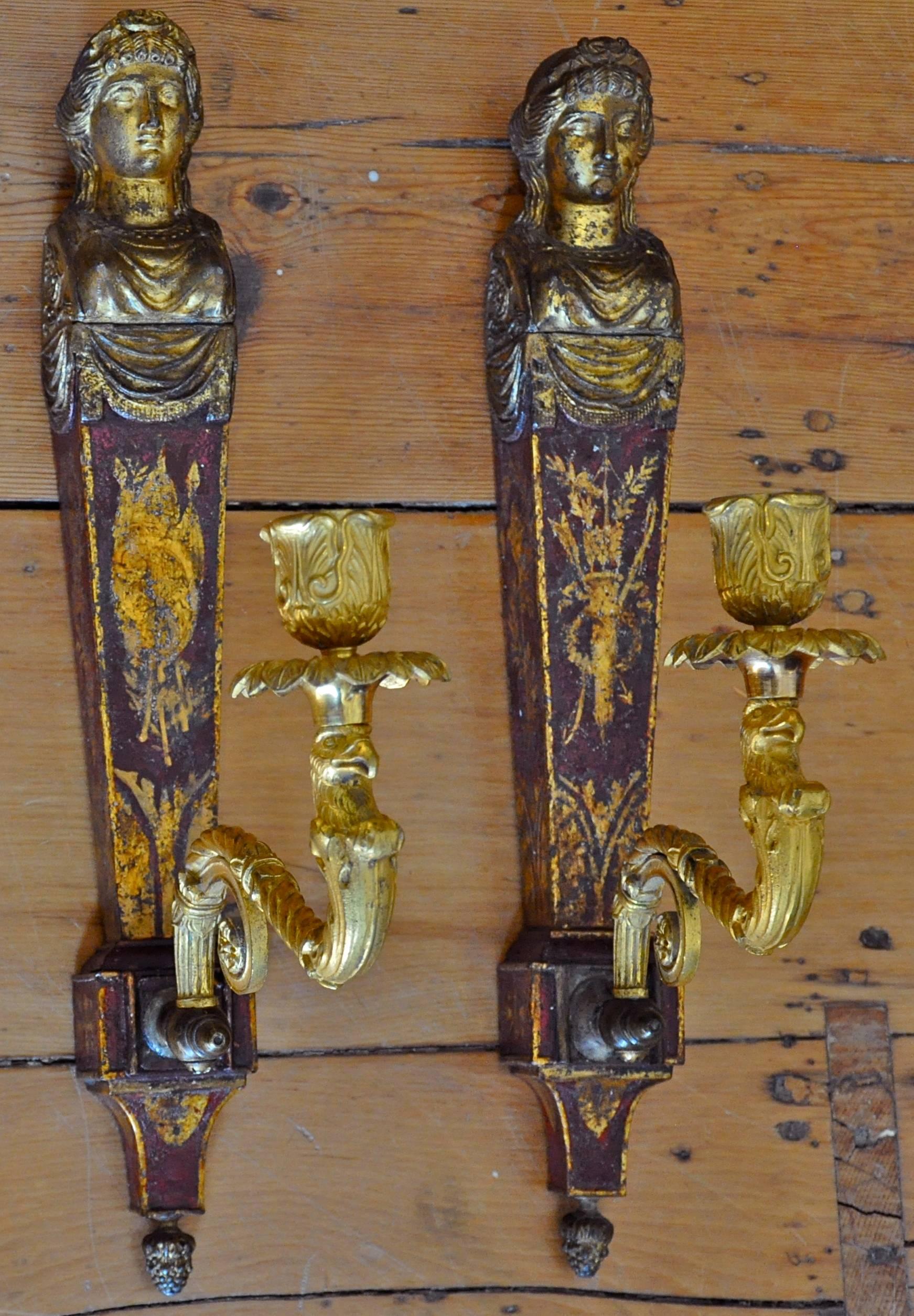 Period French Empire one arm tole and gilt wall sconces.

Red tole with neoclassical trophies
Single candle arm of eagle head
Female herm bust in gilt.