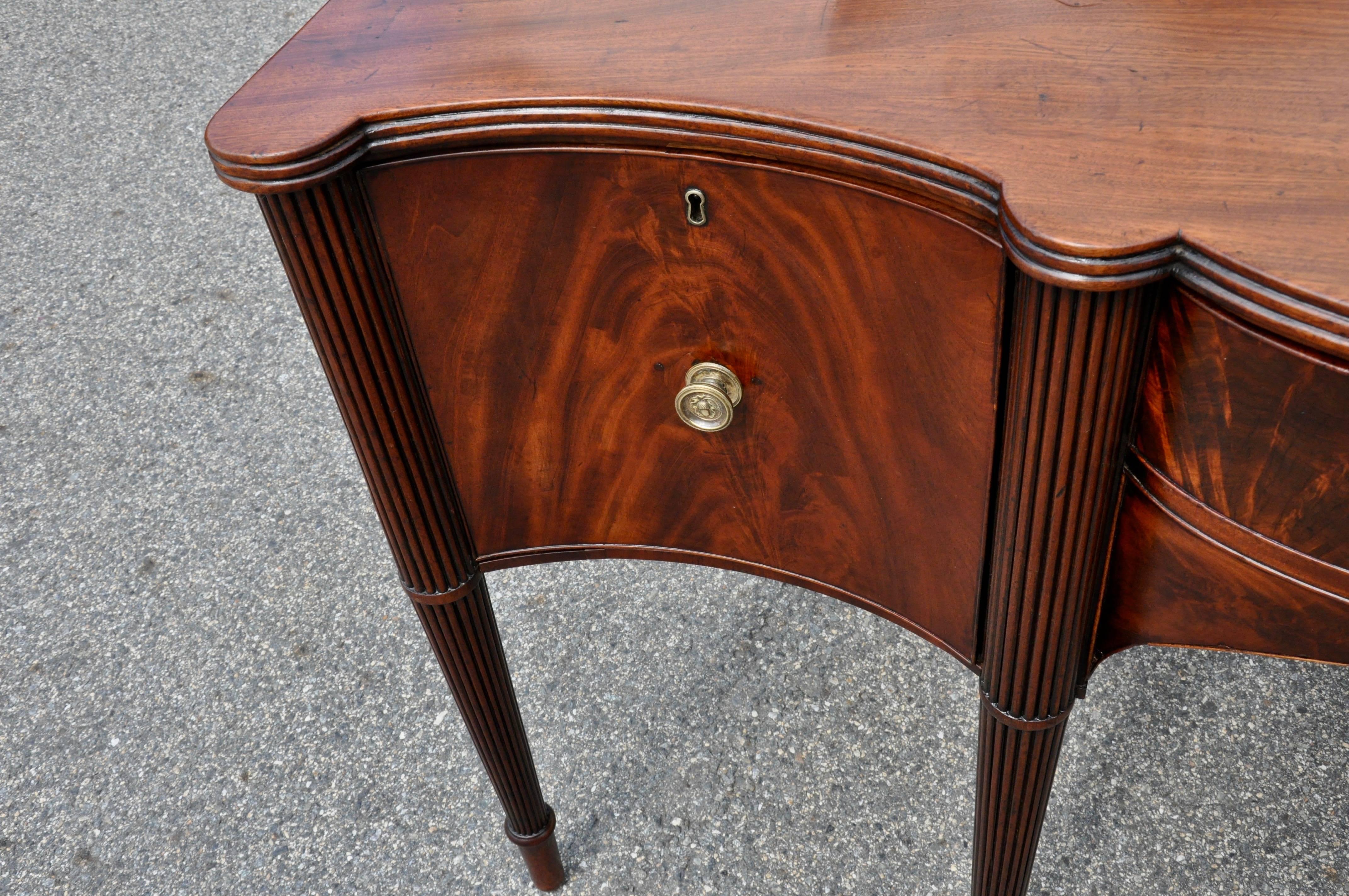 Period George III magnificently figured Cuban mahogany sideboard.

Bowfront
Original finish cleaned and waxed
Beautiful patina and color
Sectioned central drawer
Flanking side wine drawers
One board top.