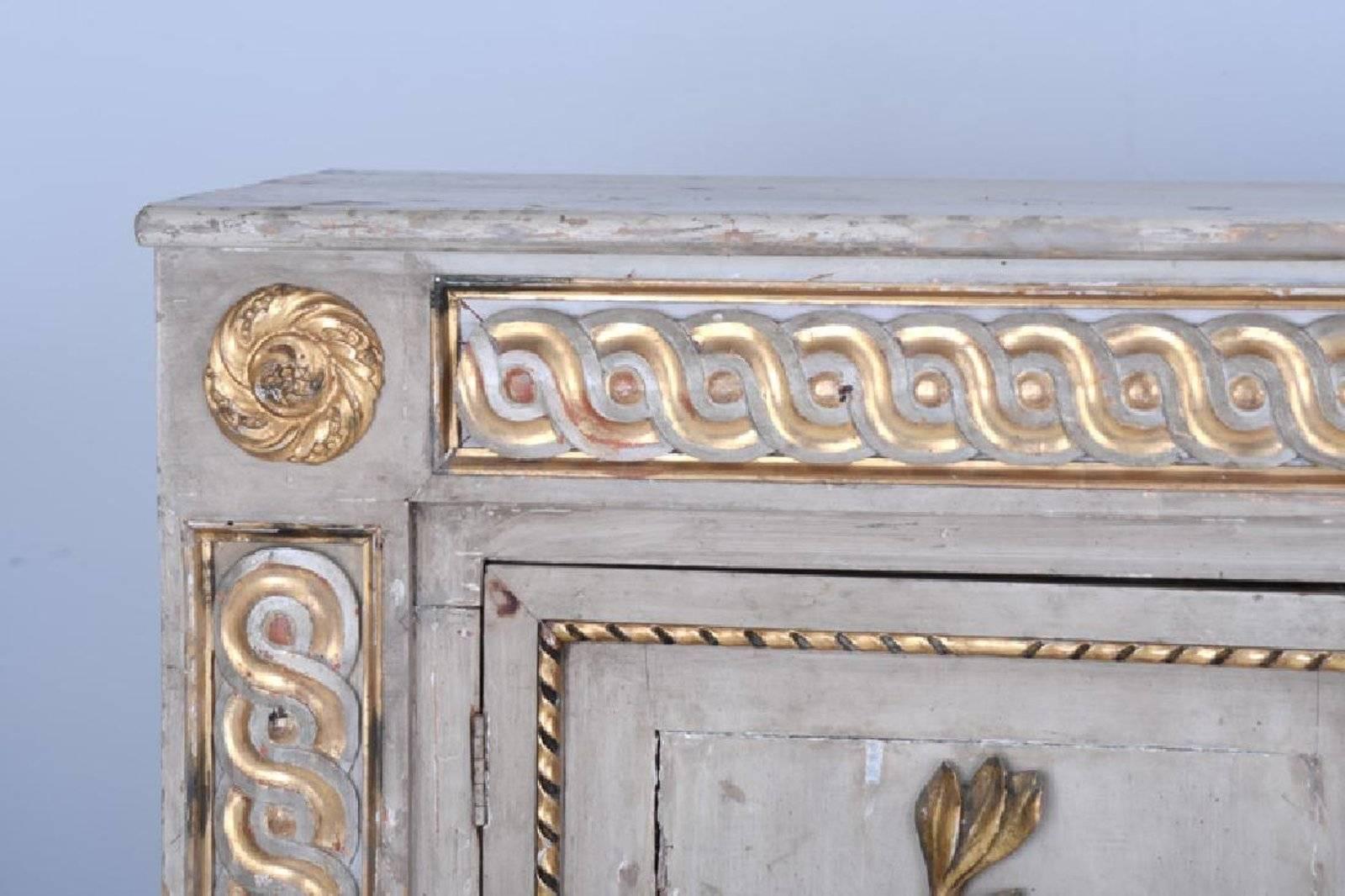 Period 18th century neoclassical sideboard cabinet
- Exquisitely executed
- Great narrow depth
- Three cabinet doors of naturally carved wooden laurel and oak leaves in original gilt
- Gilded guilloche.
       