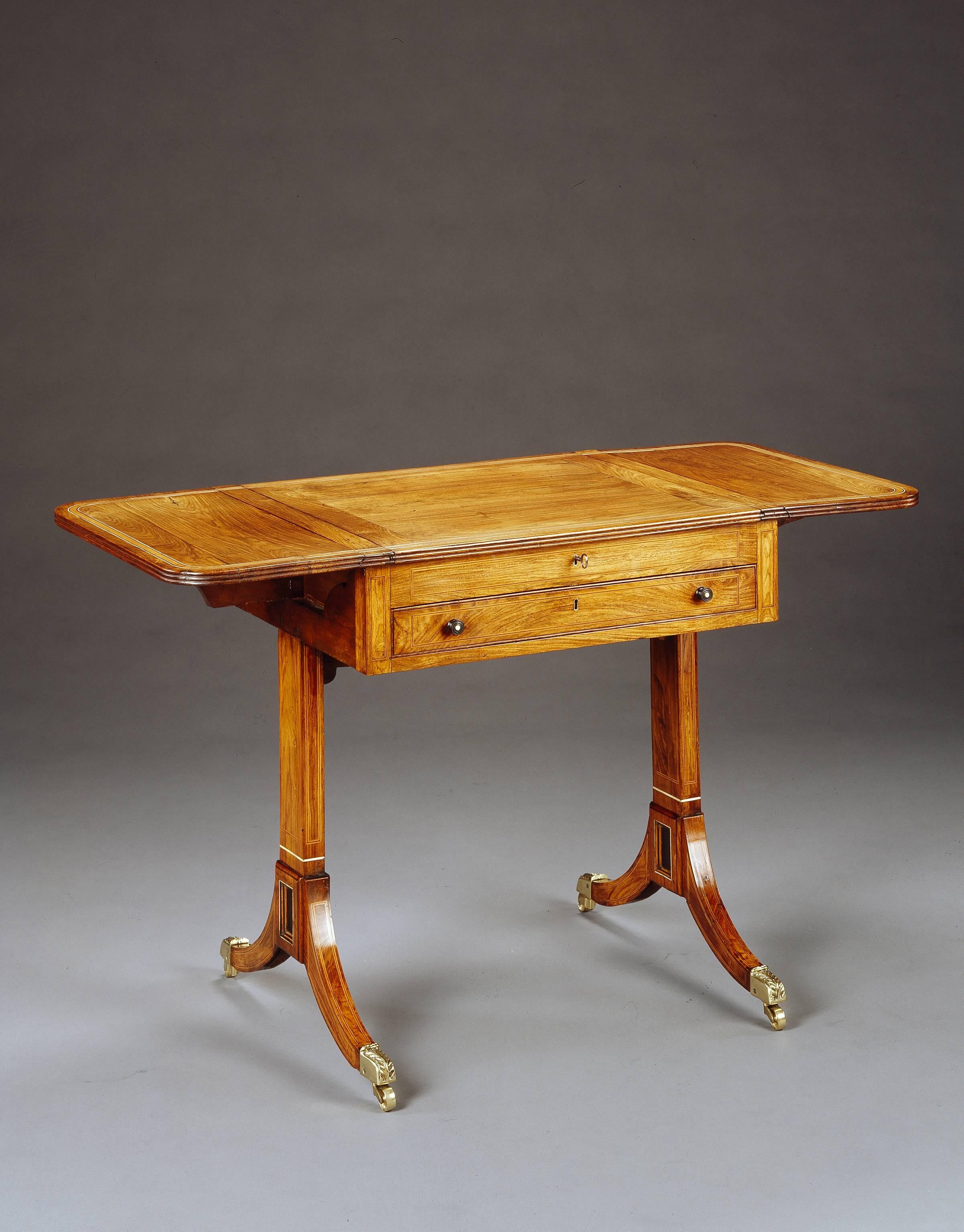 An early 19th century Anglo-Indian padouk games table, the rectangular top with rounded corners and a satinwood border, the removable central section between two flaps and with a chess board on the reverse, enclosing a removable inlaid backgammon