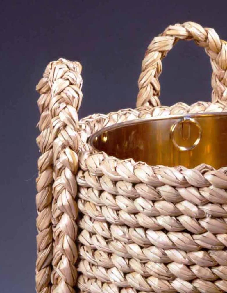 A modern rush log basket with four carrying handles and a polished brass liner.