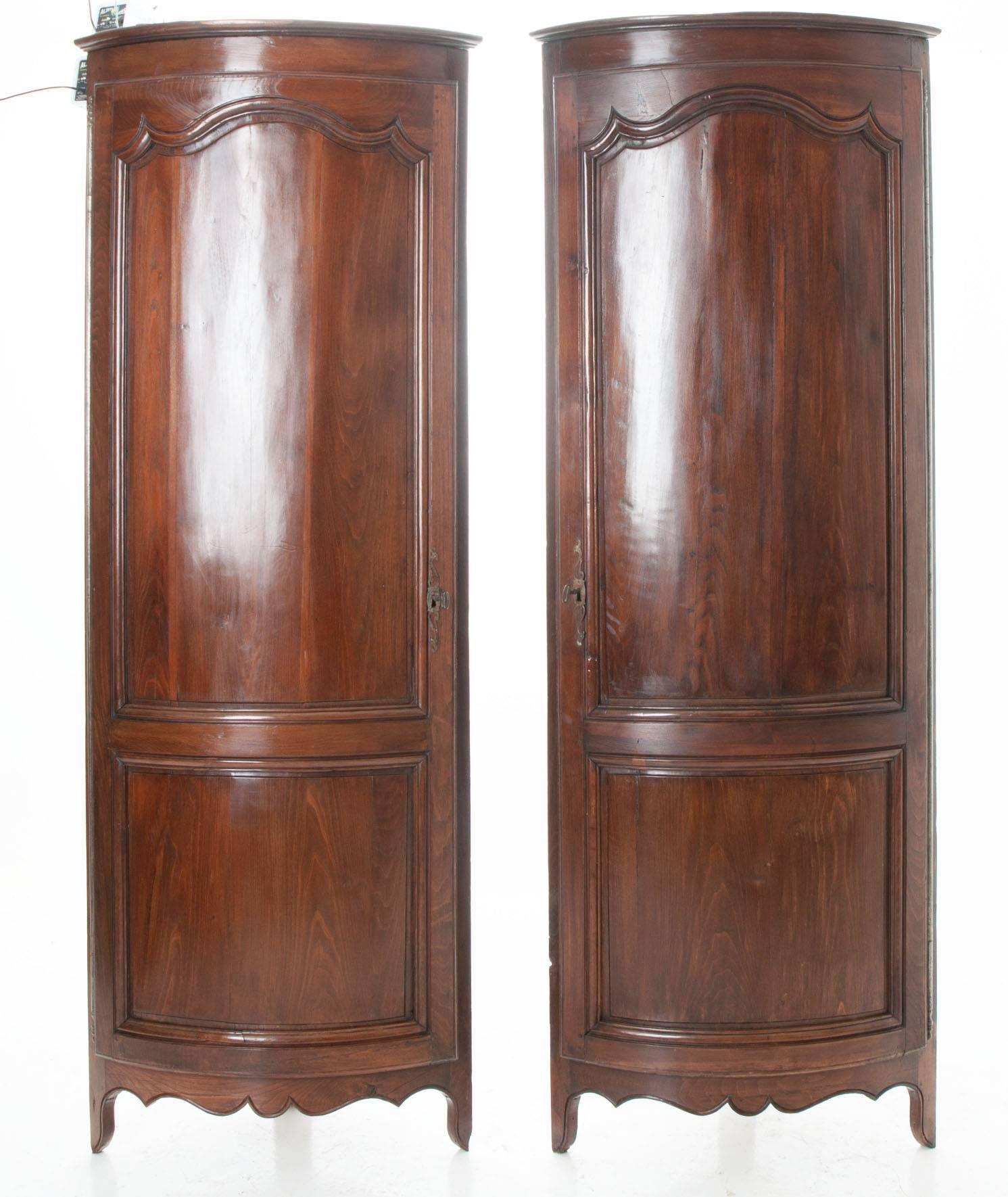 A wonderful pair of demi-lune Louis XV corner cabinets. Starting with a flat cornice down to a single demi-lune door swinging open on barrel hinges to a blue painted interior with fixed shelves. The locks, all original and in working condition.