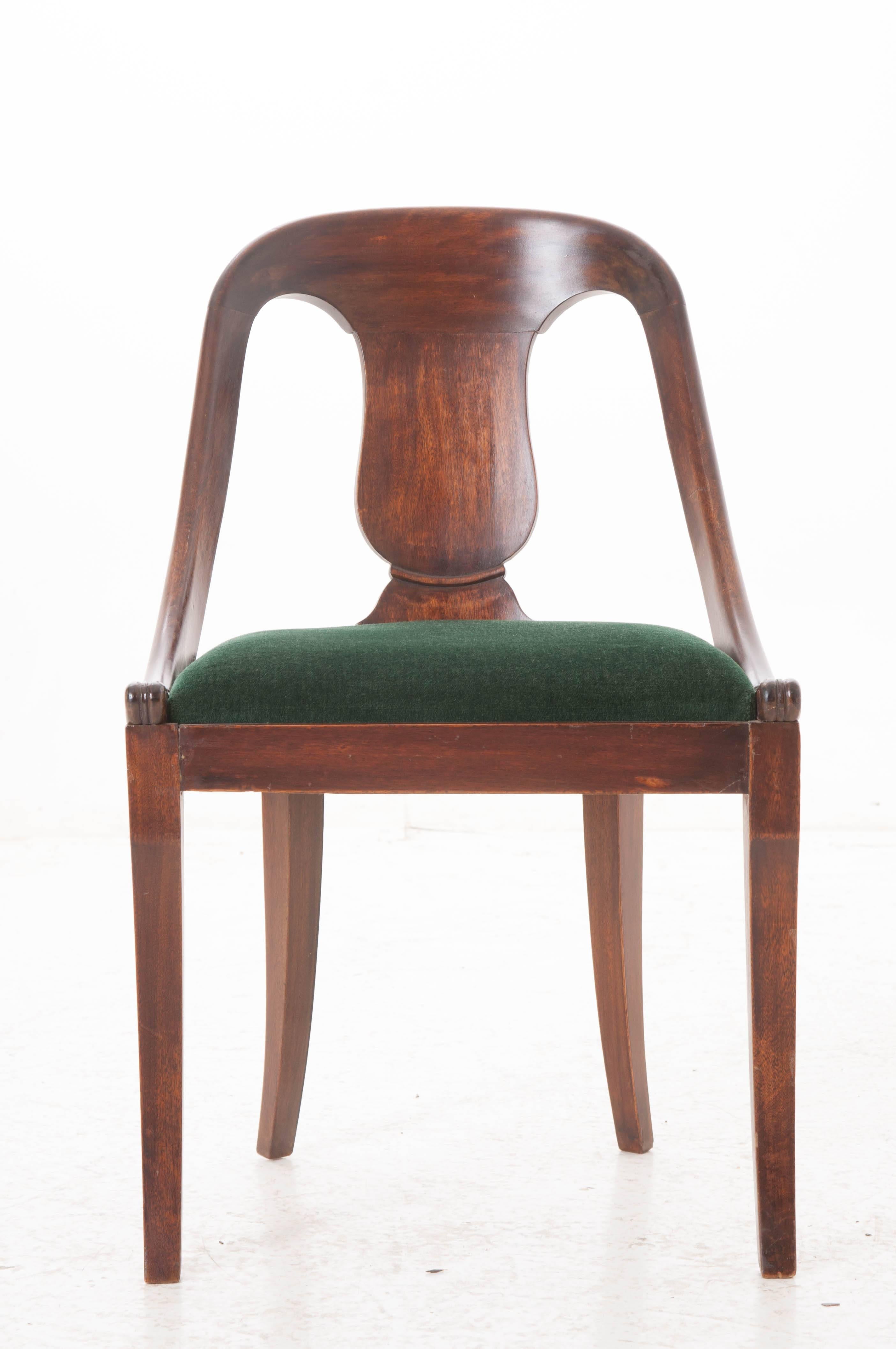 Made in the early 1900s, this absolutely adorable mahogany chair may be lacking in stature, but more than makes up for it in personality. Beautiful, rich, dark stain brings the mahogany to life. From the gracefully curved back extends two implied
