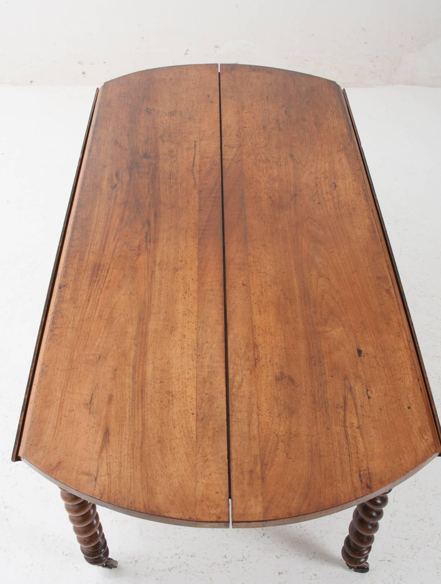 This drop-leaf side table has a rich cherry patina all around. Two wide planks make up for the center of the table while single plank demilune leaves drop to the sides. This table can expand with additional leaves as the center of the table pulls