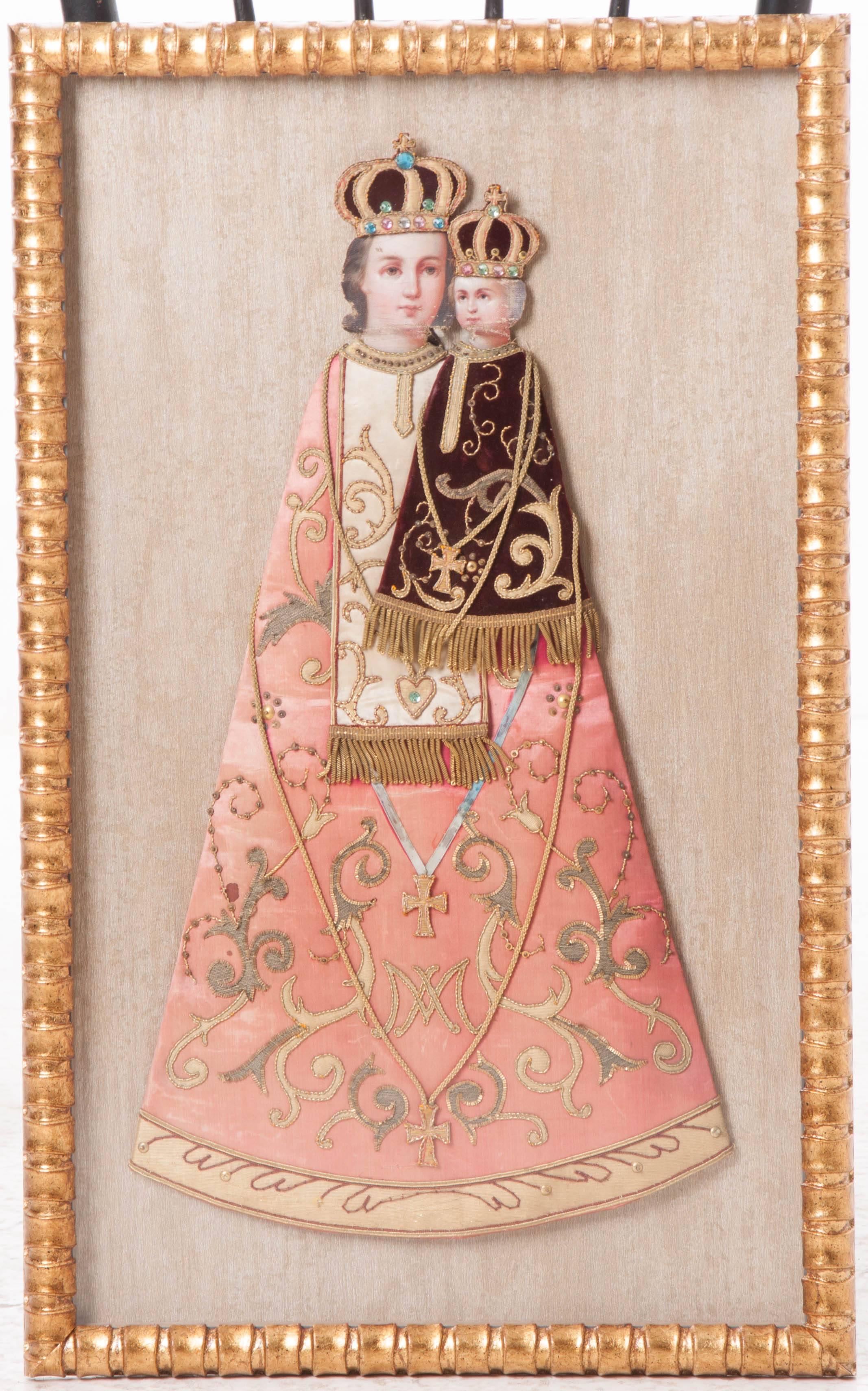 Framed antique textile, taken from a religious banner of Christ Child with Mother, Mary dressed in fine silk and velvet with raised gold metallic embroidery and cording. Set in a new gold gilt frame with metallic mat board.