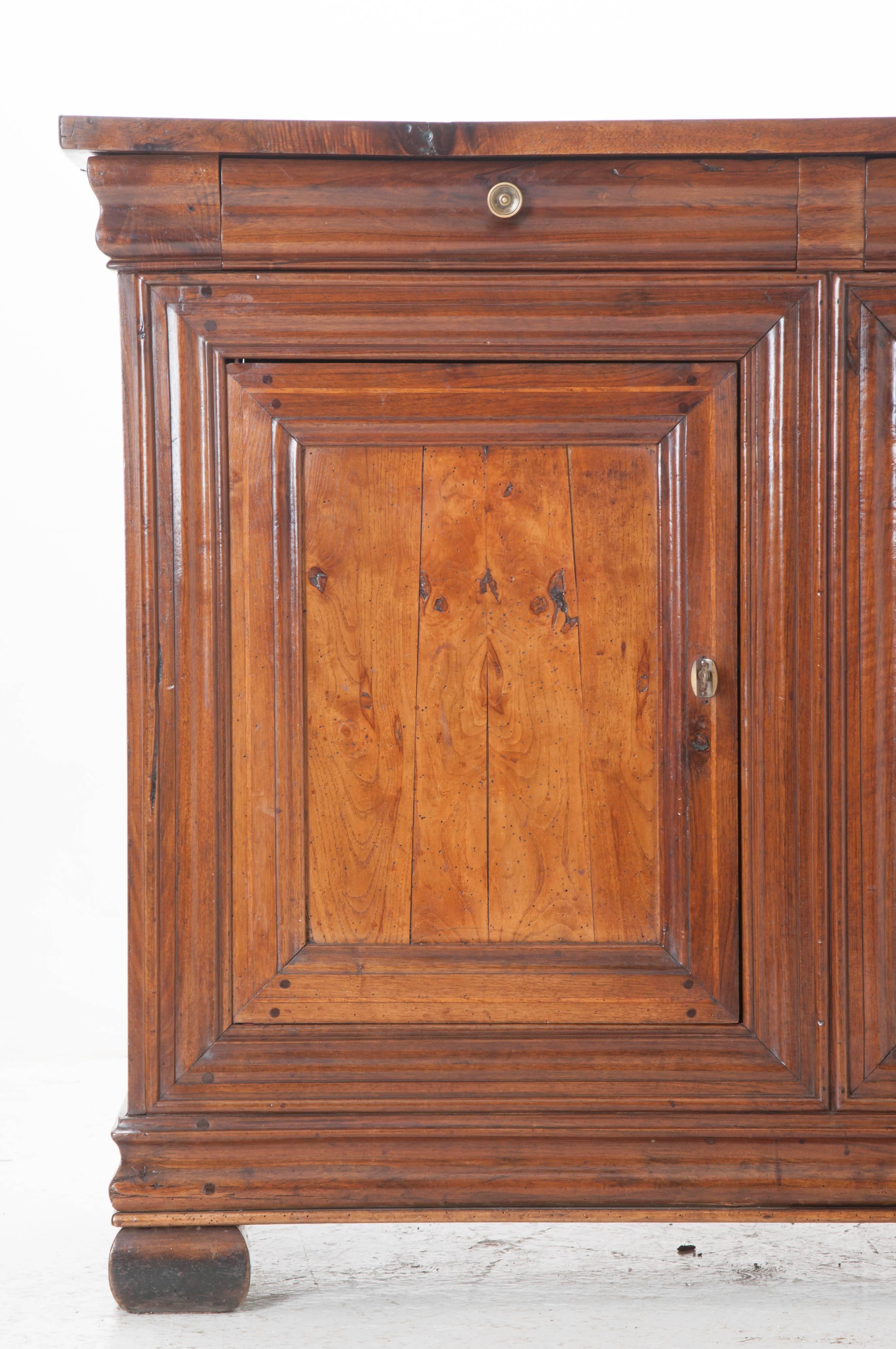 A Louis Philippe walnut enfilade with three drawers situated above three doors from 19th century France. The doors, equipped with working locks and hidden hinges, conceal a storage cavity equipped with a single fixed shelf. This solid walnut