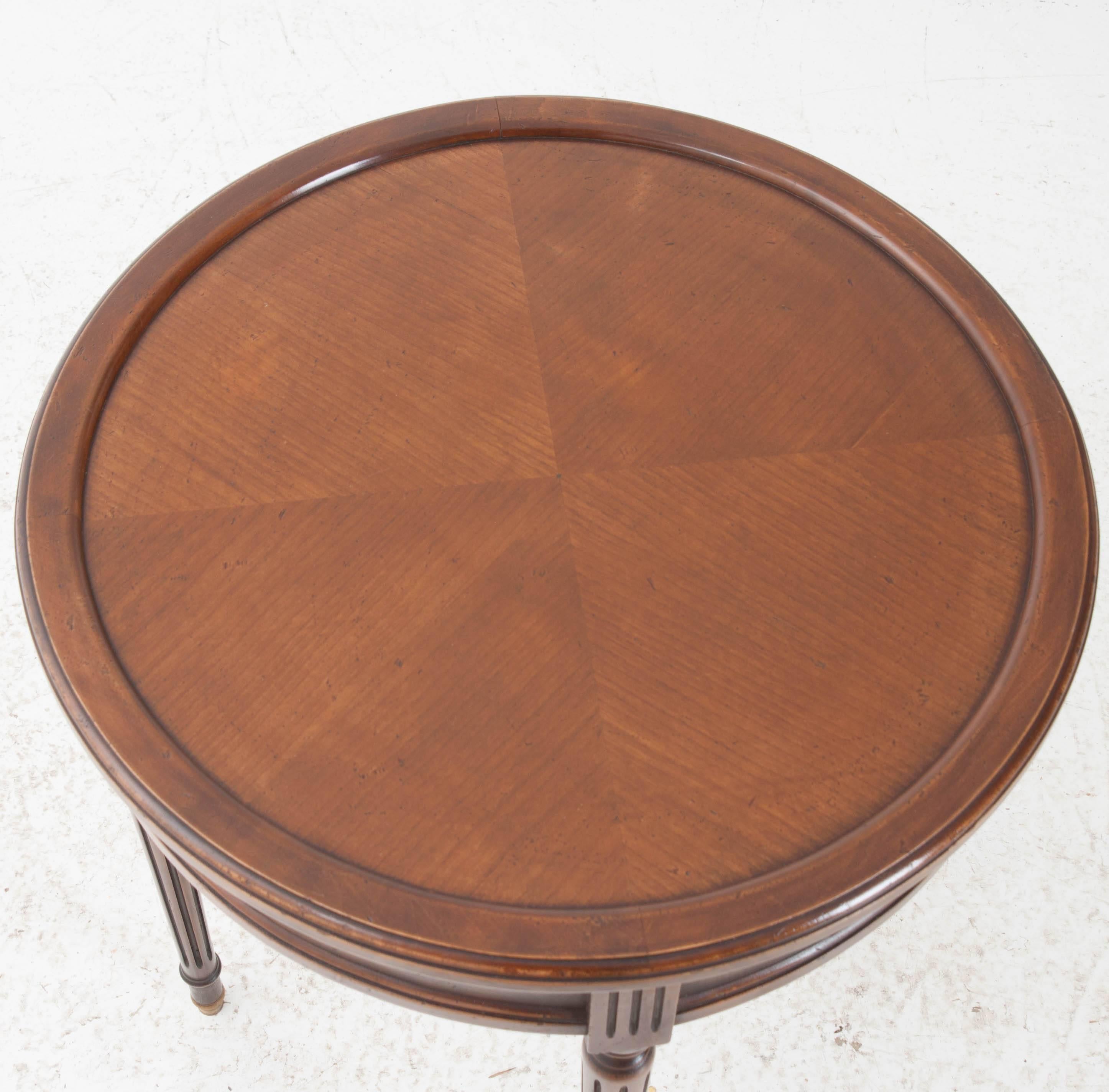 An amazing French walnut Gueridon table from the early 20th century. Careful attention was paid when aligning the exquisite striped walnut veneer found on the table's top. Two drawers and two leather topped slides can be found in the apron. The