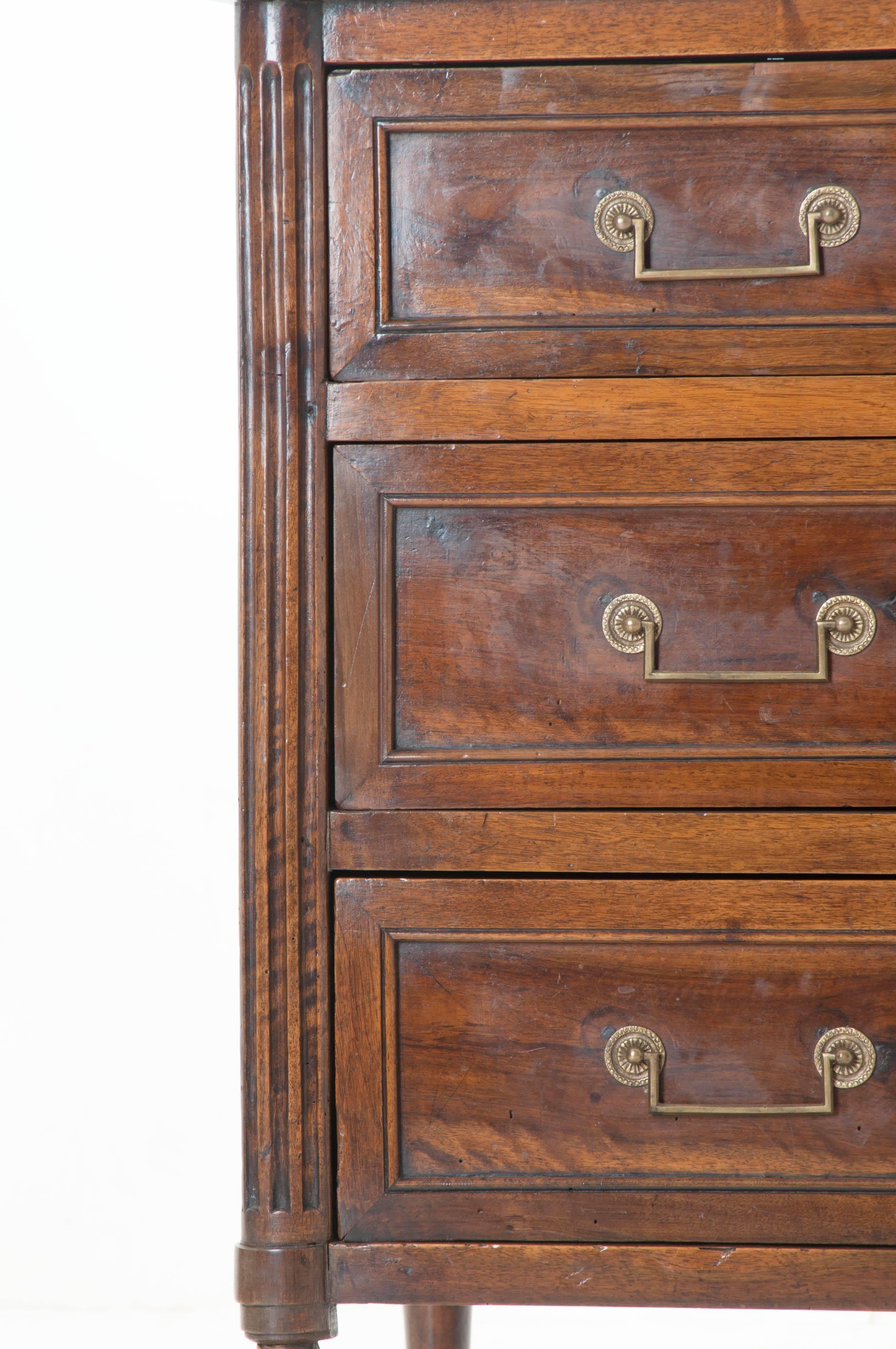 A French 18th century Louis XVI style walnut three-drawer commode. Two hundred forty years have left an impeccable impression on the walnut used to create this exceptional commode. The three drawers are each outfitted with two brass bail handles and