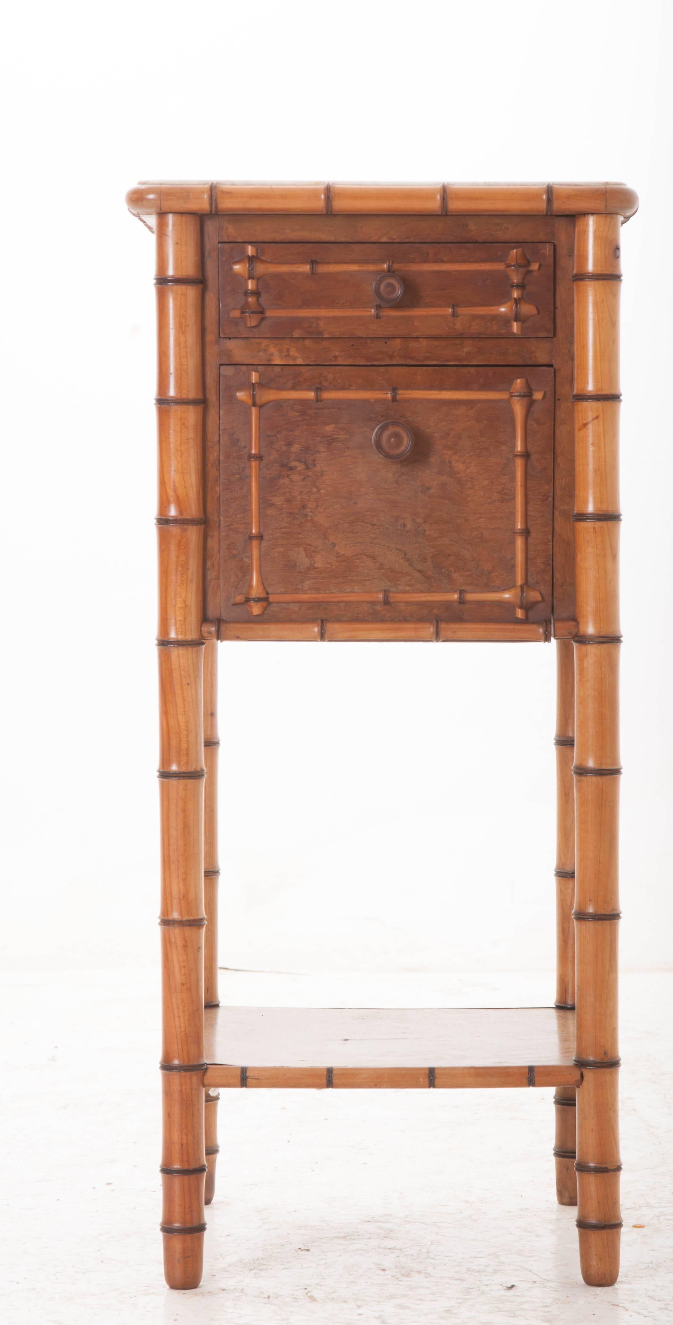 A fantastic carved faux bamboo bedside table with white marble top from 19th century France. A single drawer can be found above the door, both embellished with carved, crossed bamboo trim. The door conceals a marble lined interior cavity. Both the