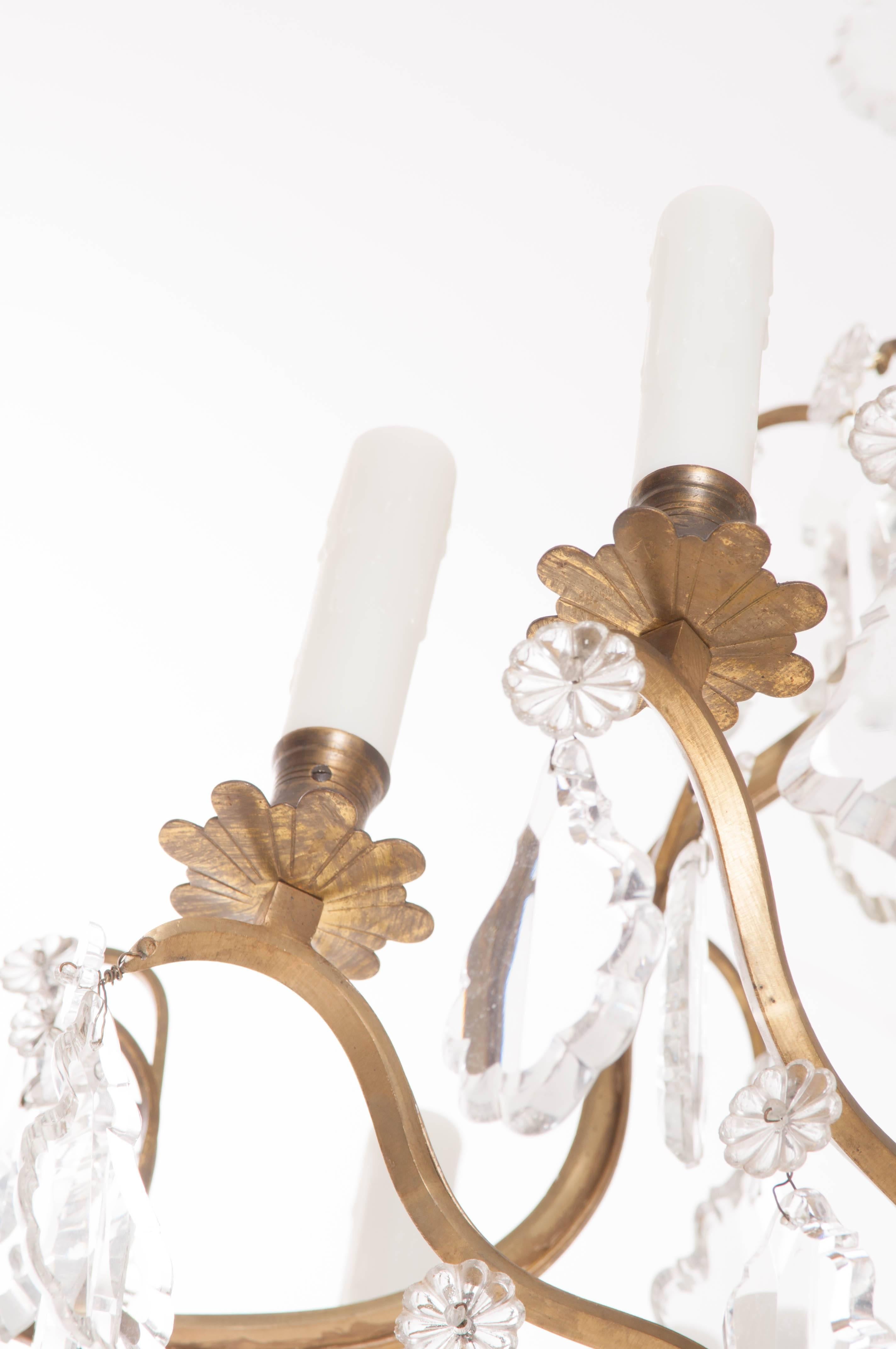 This beautiful twelve-light brass and crystal chandelier comes from 19th century, France. Wonderful clear crystals drop from the brass birdcage frame, with the attachment points hidden by crystal rosettes. Four interior lights add to the eight