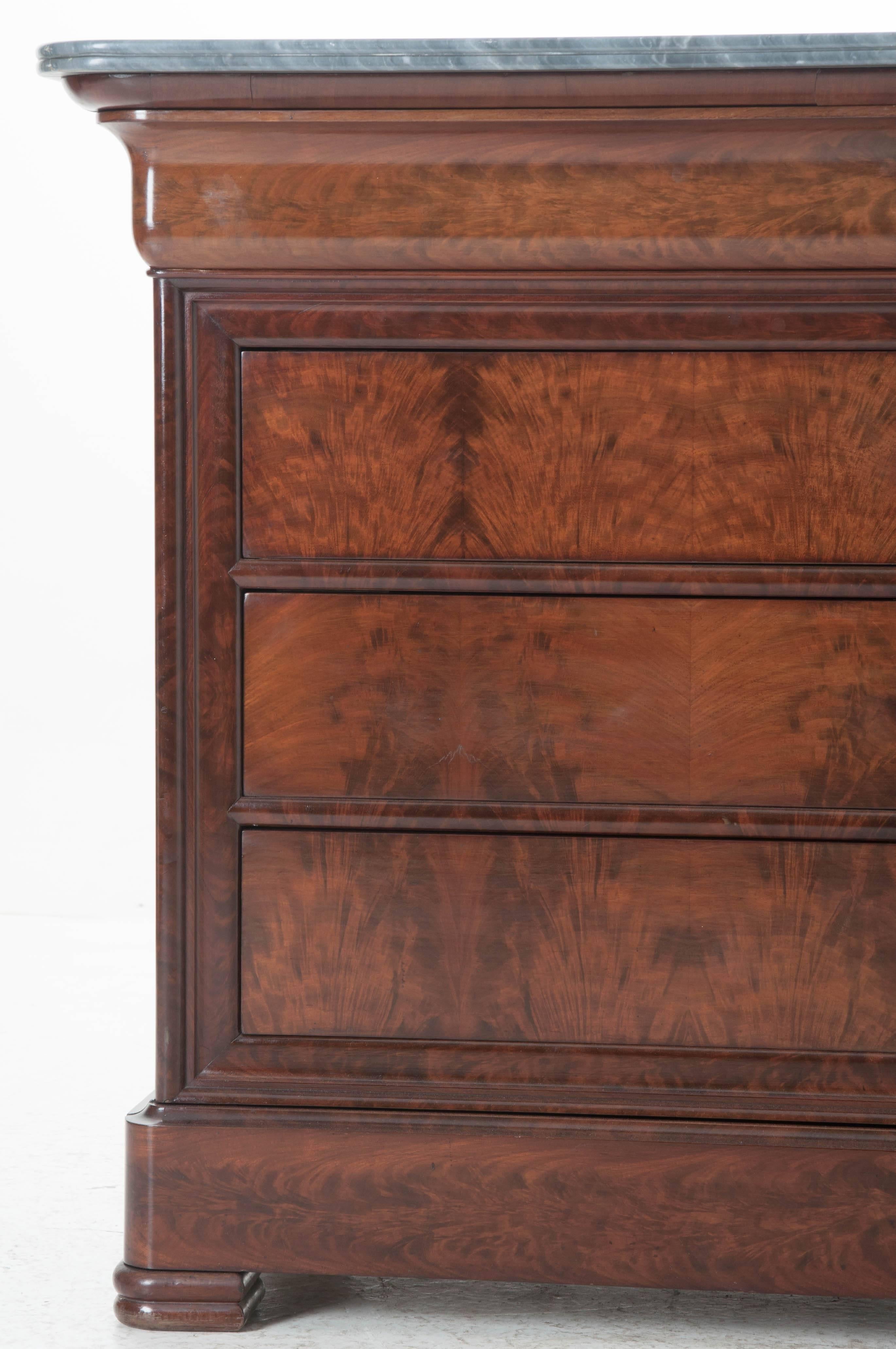 A spectacular five-drawer French mahogany commode with exceptional gray marble top. Louis Philippe style is refined, linear, and restrained. This Louis Philippe commode is all of that and more. The facade is finished in meticulously bookmatched