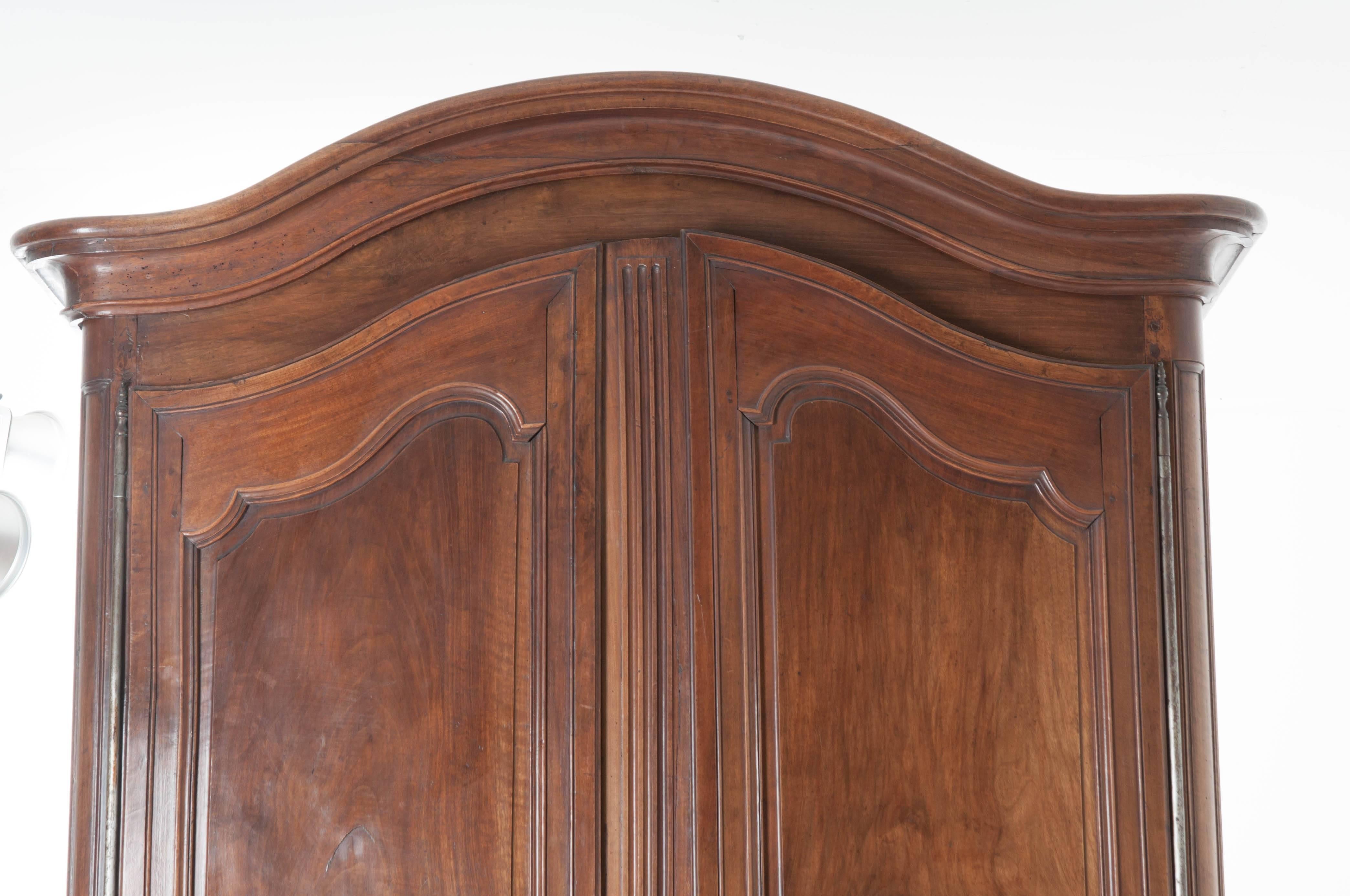 An absolutely stunning hand-carved walnut armoire from 19th century France. It's tallest point, the crest of its Chapeau de Gendarme crown, measures just over nine feet tall. Two large, shaped doors equipped with working locks are hung on barrel