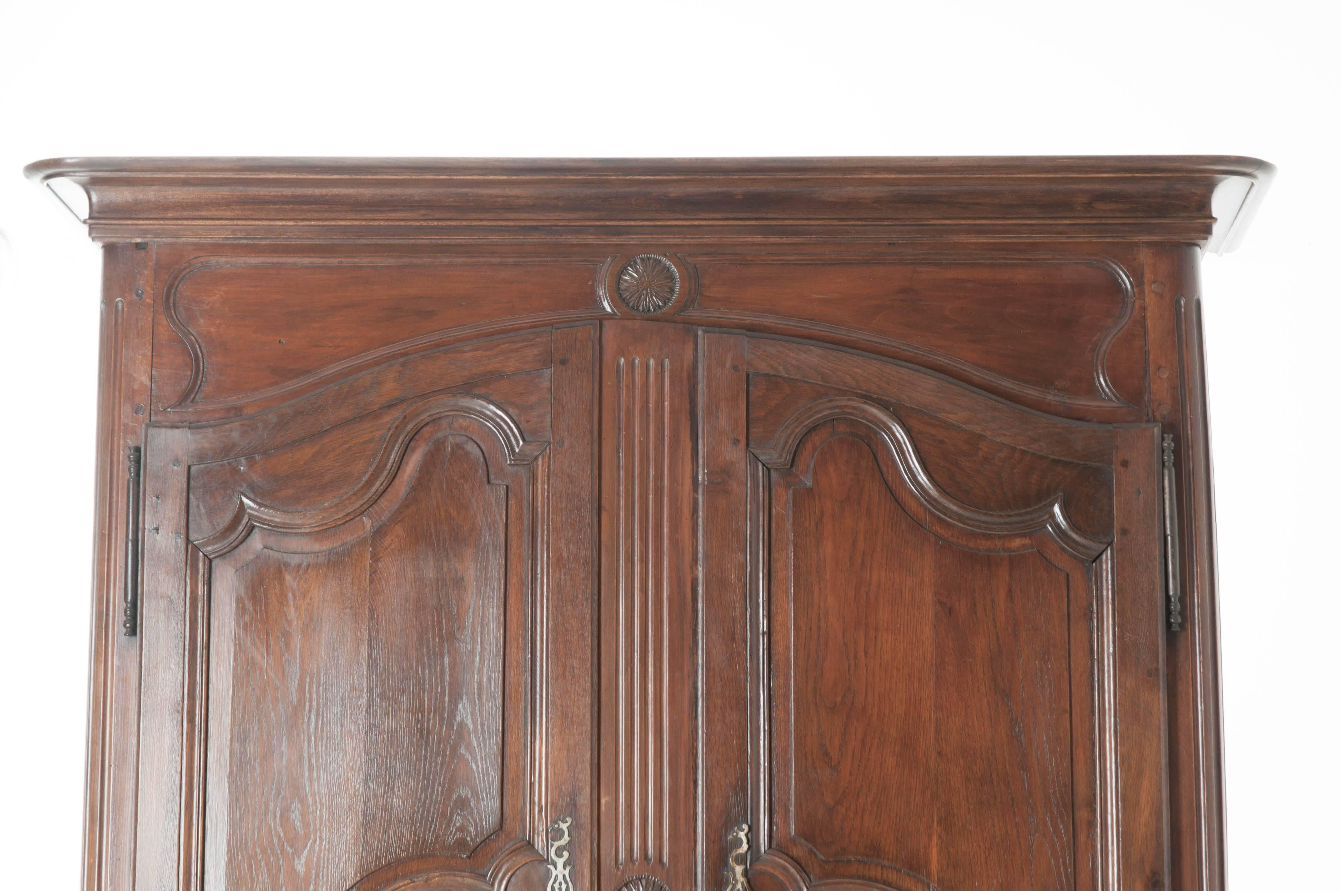 Totally carved by hand, this 18th century oak buffet a deux corps boasts not only wood with an exceptionally well aged patina, but also impeccable craftsmanship. The upper portion features two shaped doors with carved shaped panels, circular flower