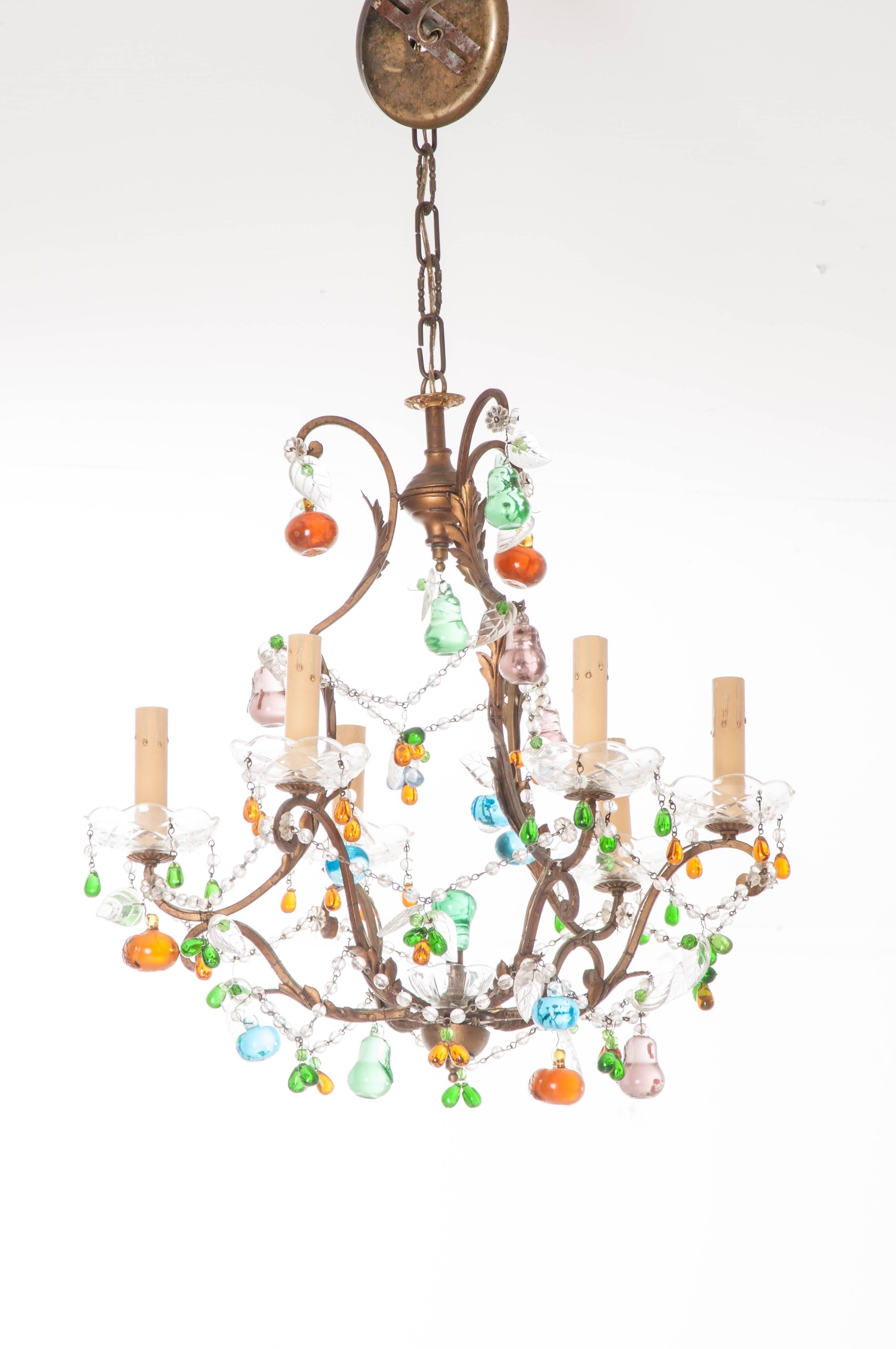 Multicolored crystal fruits and ornamentation hang from the brass birdcage frame of this playful 19th century French chandelier. Crystals in greens, blues, yellows and oranges can also be found suspended from beaded garlands that crisscross the