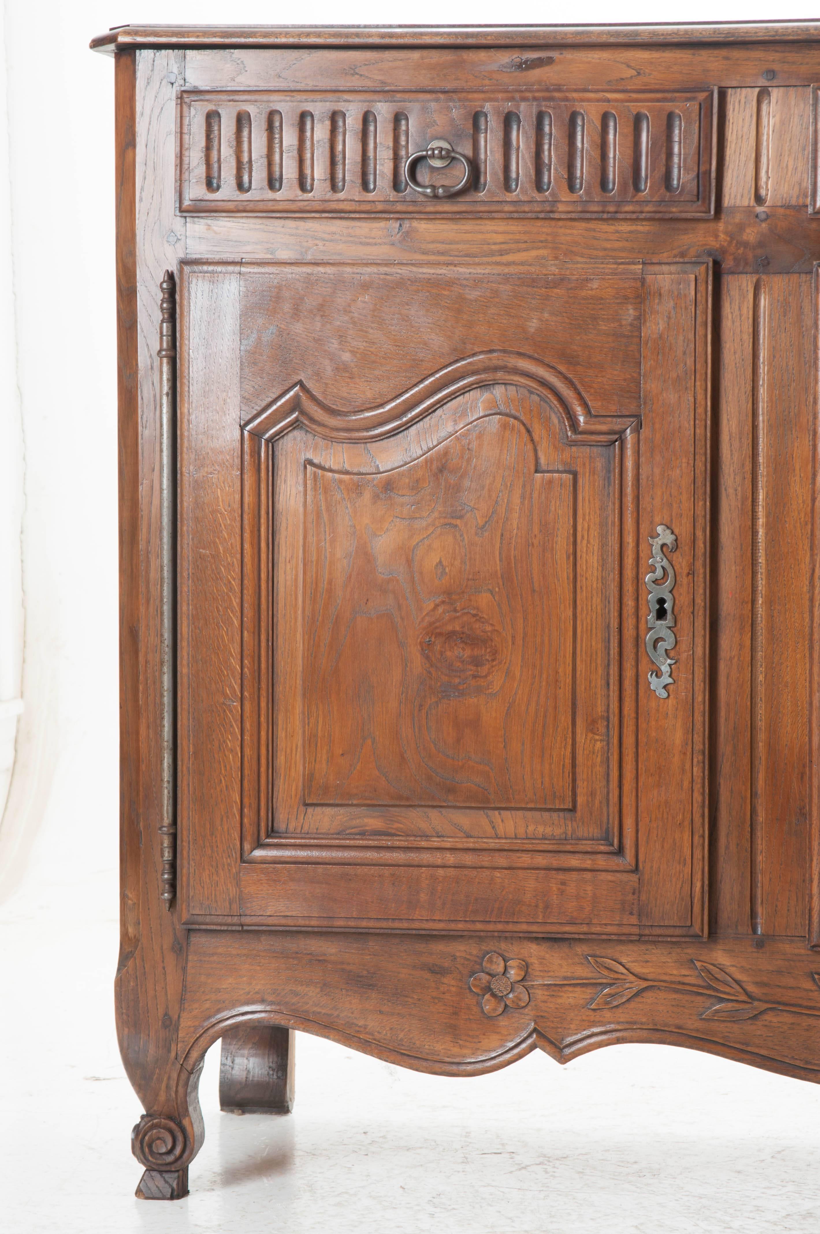 Provincial charm pours from this fabulous French oak three door enfilade. Made in 1880, this transitional piece combines elements of both Louis XV and XVI styles. Three drawers, bedecked with fluted carvings and original pulls are set above three