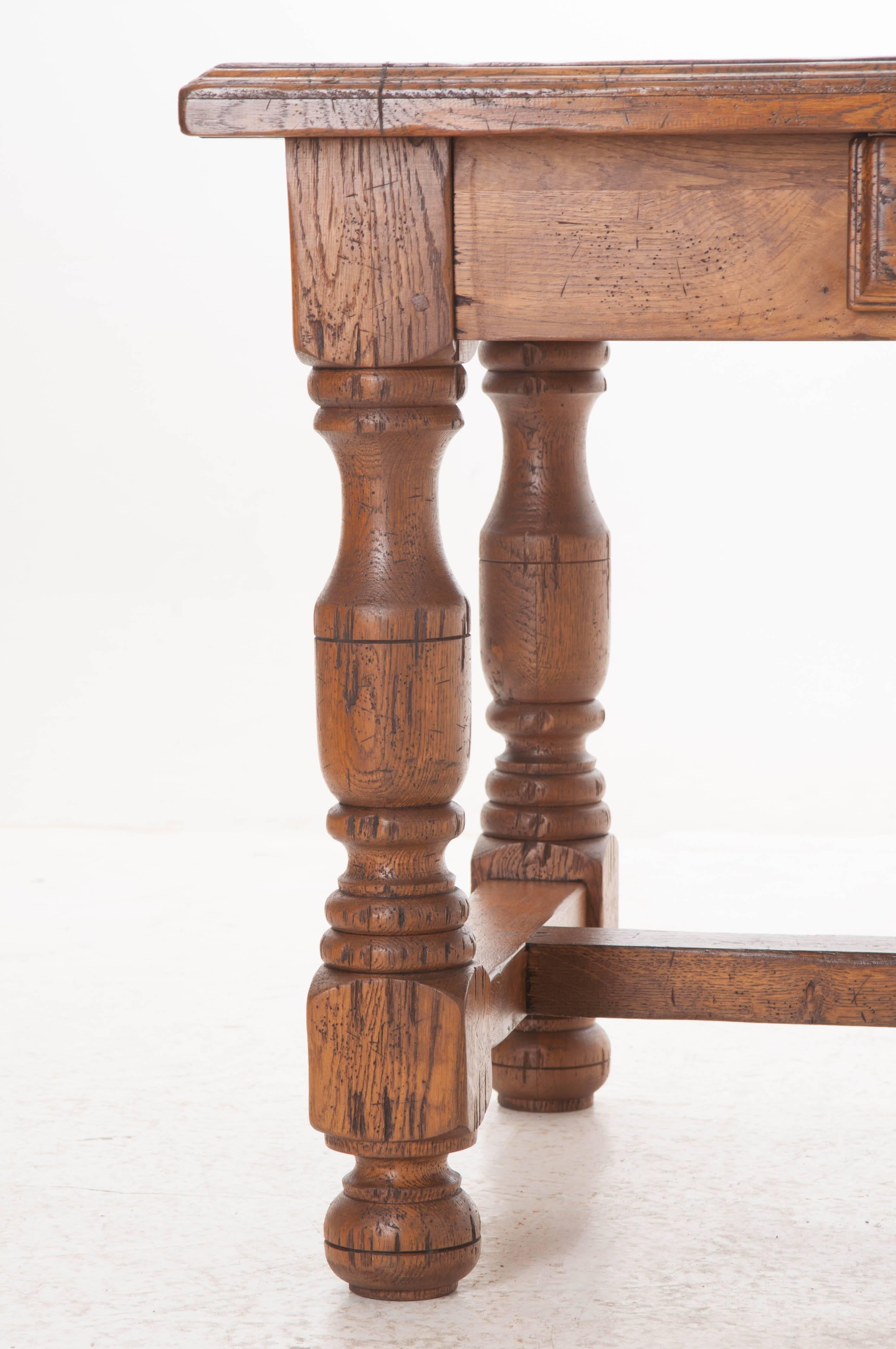 This wonderful French solid oak table was made circa 1860 using thick, weighty pieces of honey toned oak. A fresh coat of French wax and hand-polish have amplified the natural beauty found in the antique oak. The table has a drawer found in the