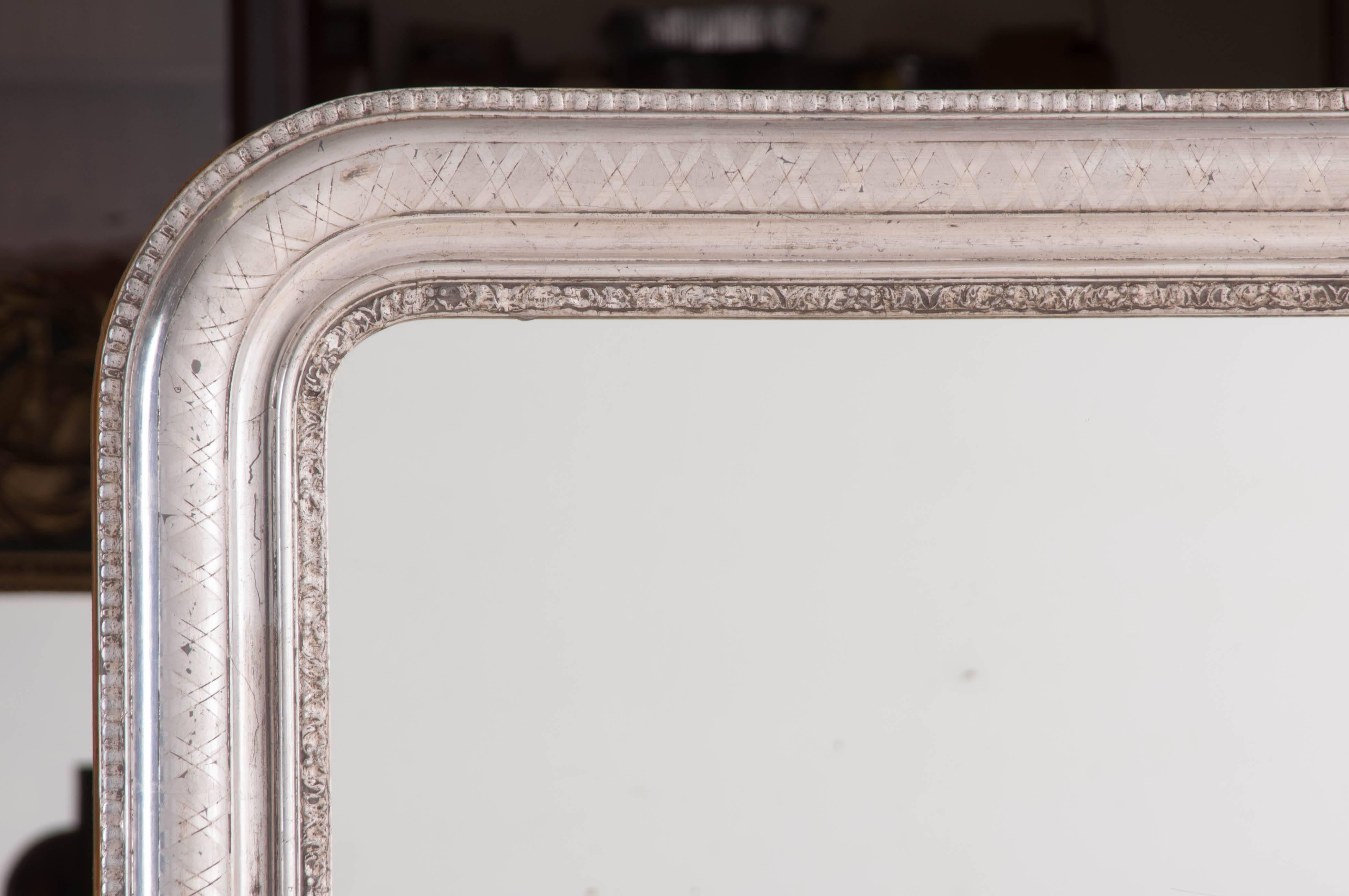 A beautiful, large Louis Philippe silver gilt mirror from 19th century, France. This Classic mirror will look amazing in any space. The frame has been embellished with a criss-crossed motif created with the metallic silver gilt that surrounds the