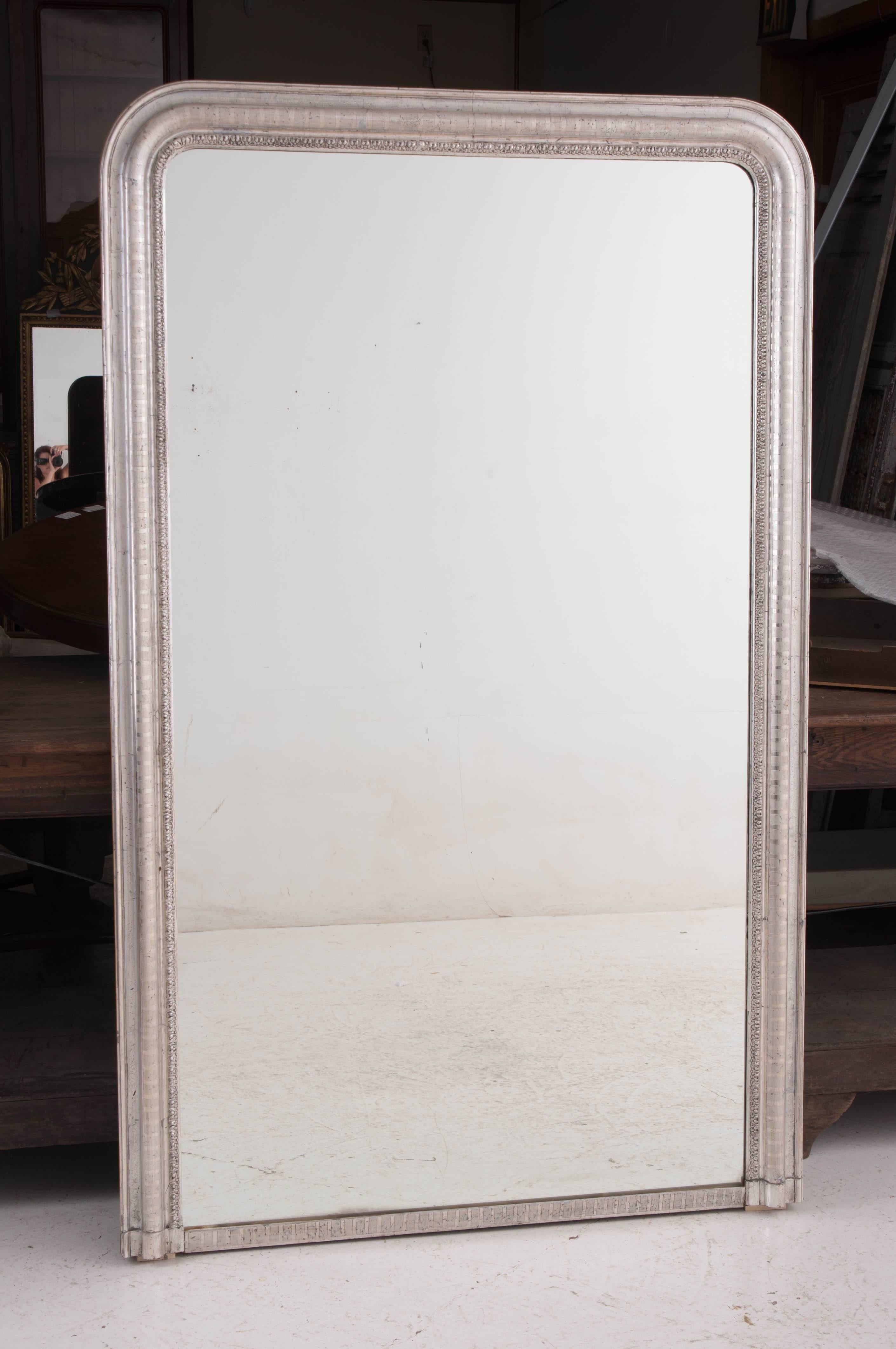 A tall, spectacular Louis Philippe silver gilt mirror from 19th century, France. A thin stripe motif adds to the beauty of the lustrous silver gilt frame. The restrained, Classic design of the mirror ensures it will look wonderful in any room it