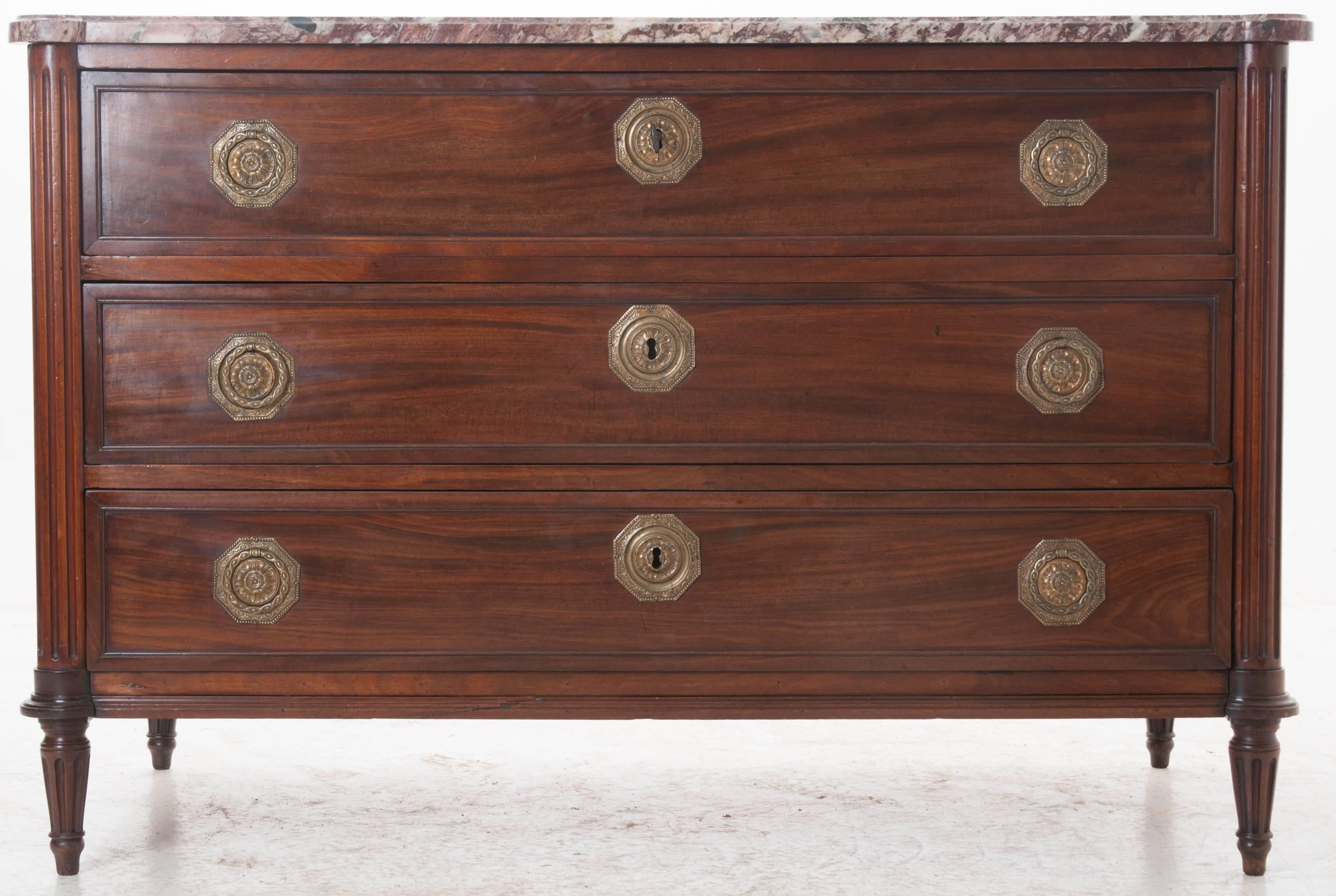 An extremely handsome French mahogany three-drawer Louis XVI commode with marble top. The extraordinary shaped violet marble top is original to the piece and in wonderful condition. The three lockable drawers are outfitted with beautiful, ornate,