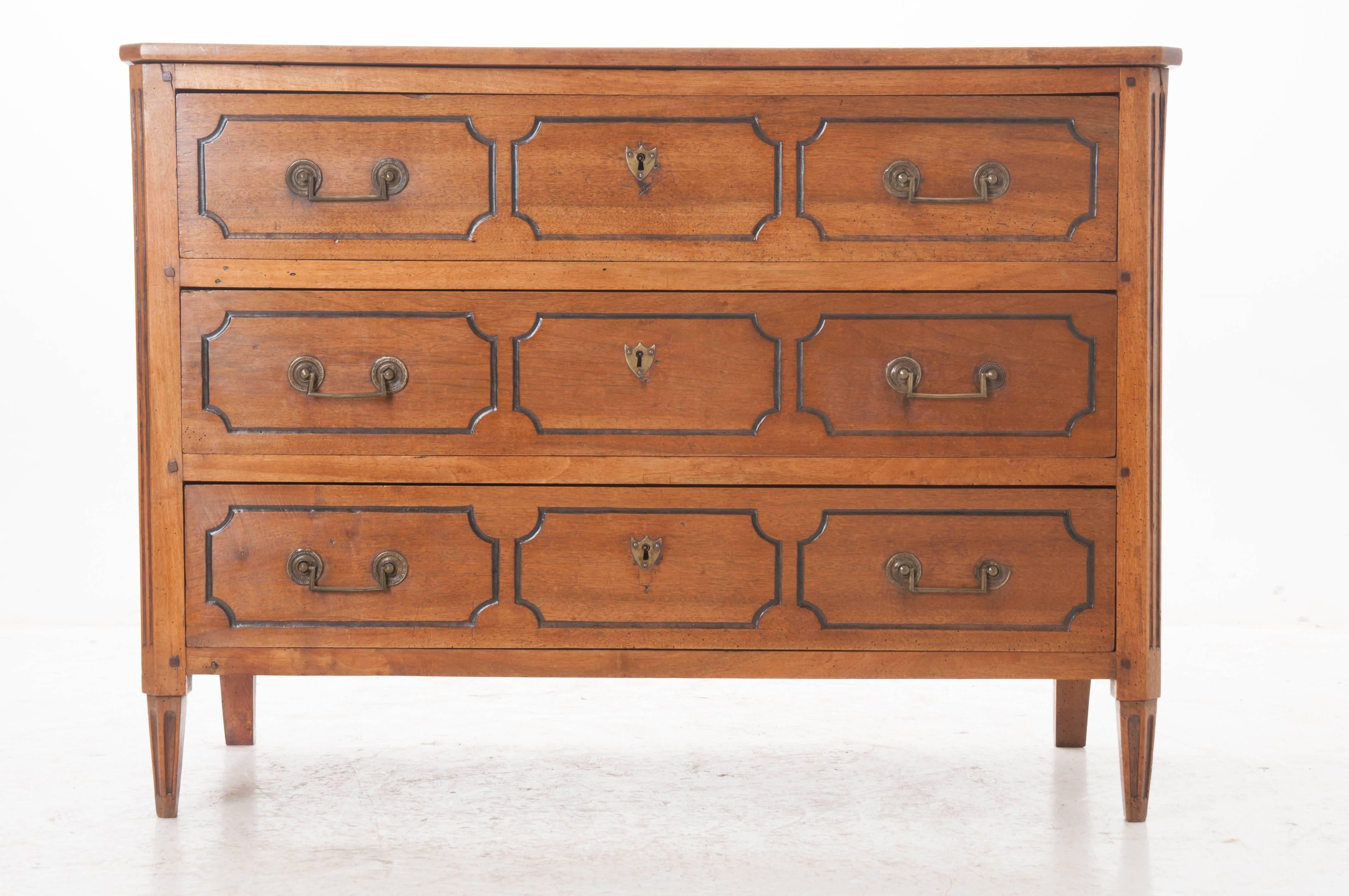 An impressive 19th century three-drawer walnut Directoire commode from France. Constructed using solid wood and peg and hole techniques, this piece has a restrained design, reflective of the Directoire style. The three drawers have shaped, ebony