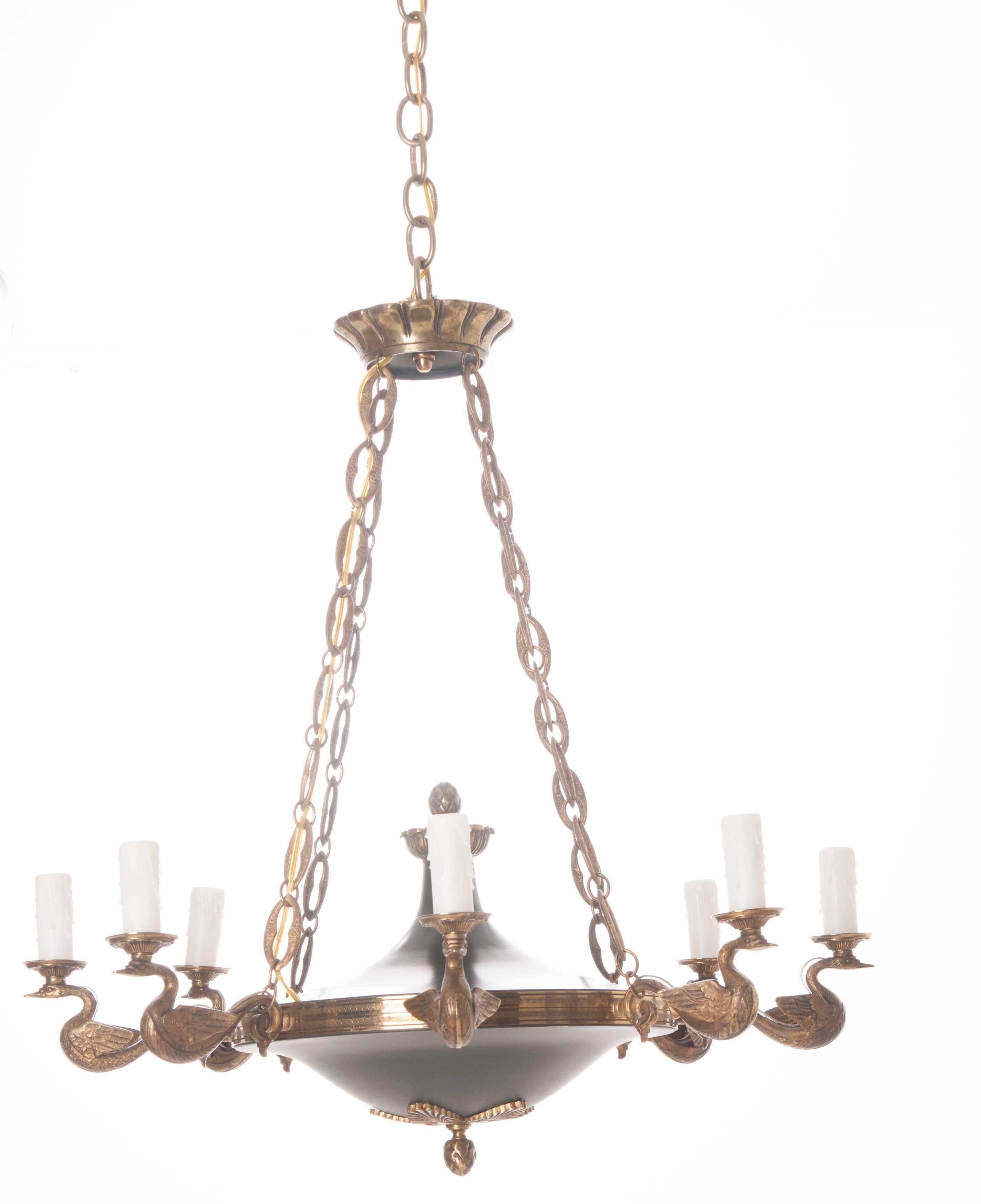 A fantastic brass eight-light chandelier from France. The eight arms are formed from beautifully detailed brass swans with brass bobeches resting on each's head. Brass artichoke finials can be found atop and below the black bottom bowl. Even the