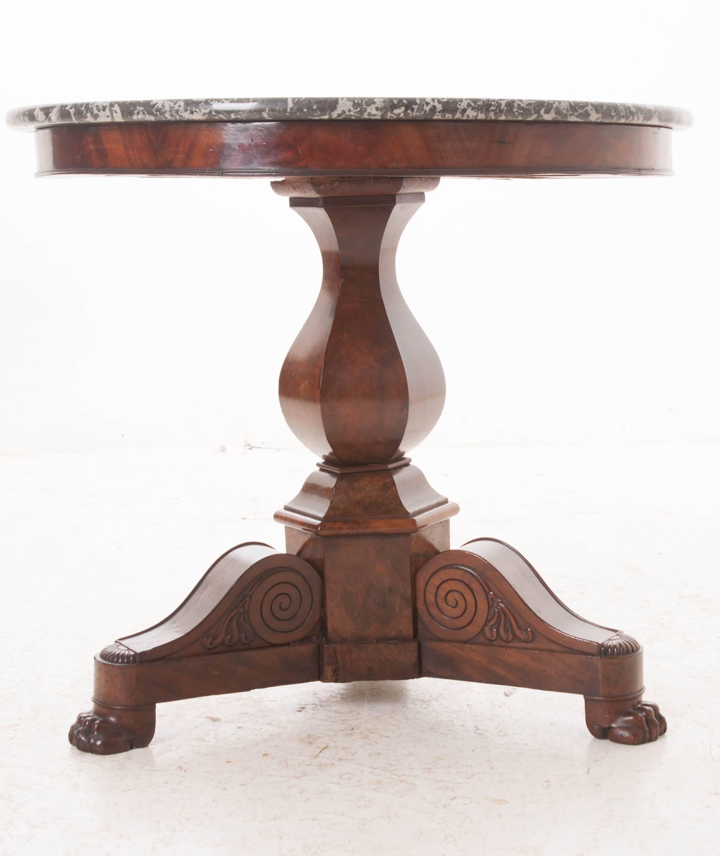 An outstanding French restauration mahogany center table with gray marble top. The marble-top is in excellent antique condition. The circular top rests on a mahogany tripod pedestal base with carved lion's paw feet. The base is embellished with